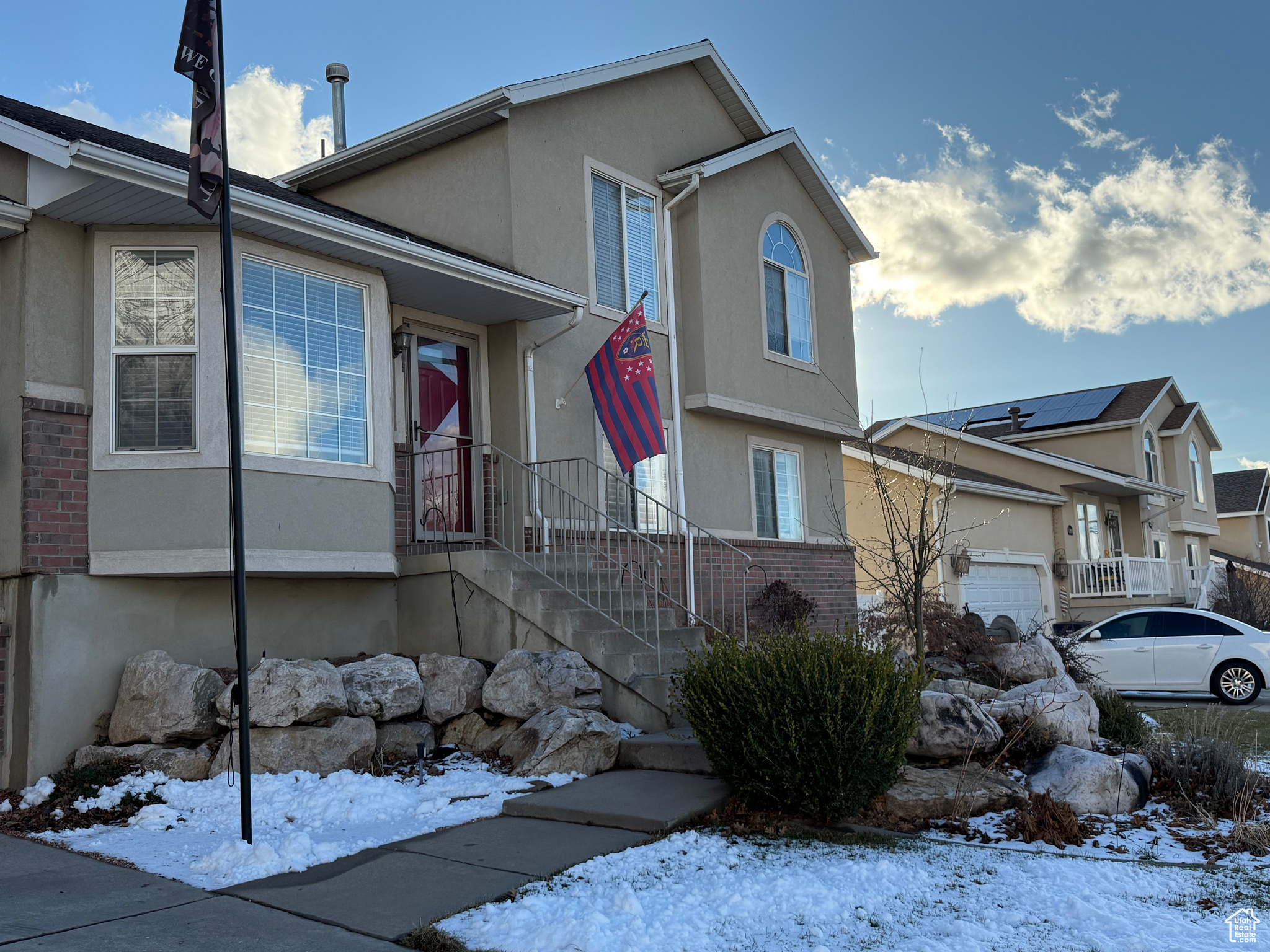 View of front of house with rock and perennials