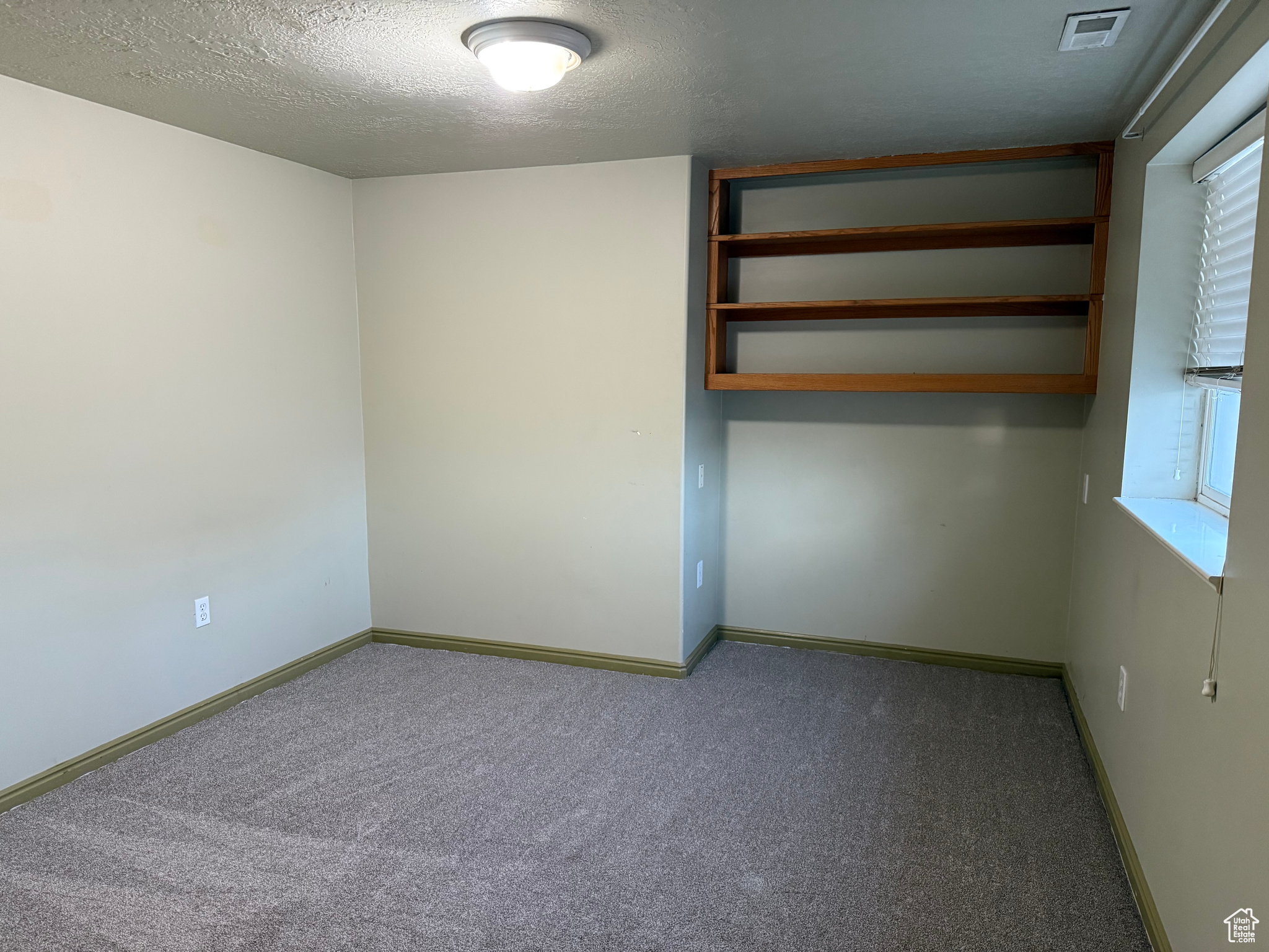 Carpeted empty room featuring a textured ceiling