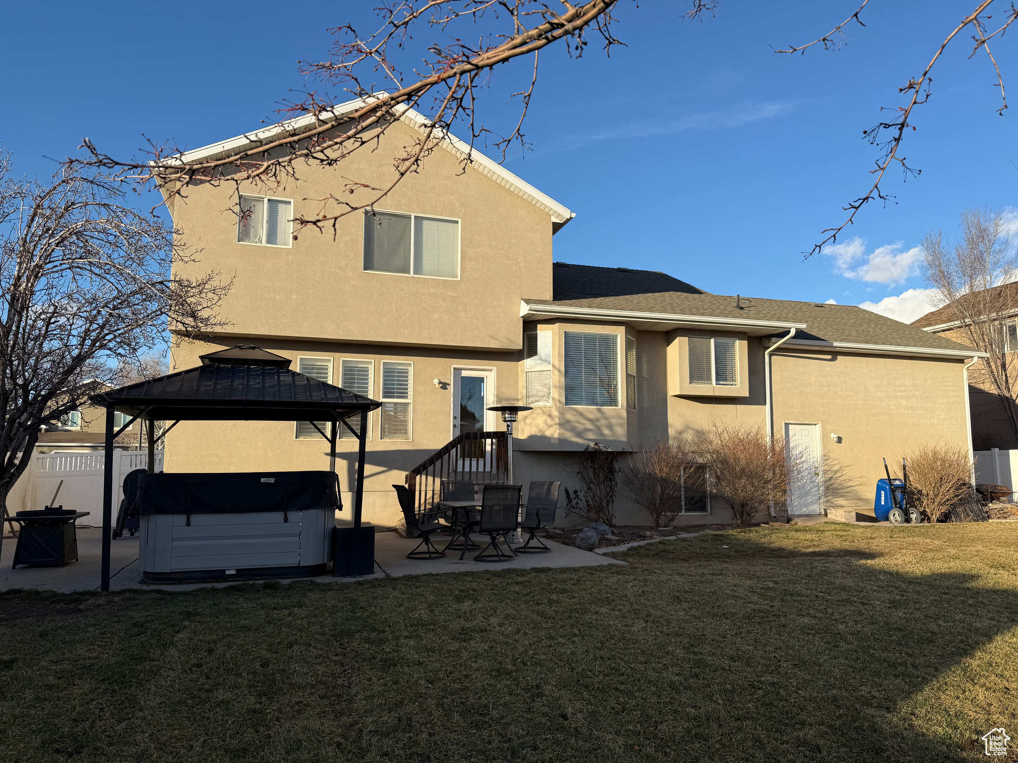 Rear view of house featuring a hot tub, a gazebo, a patio, and a lawn