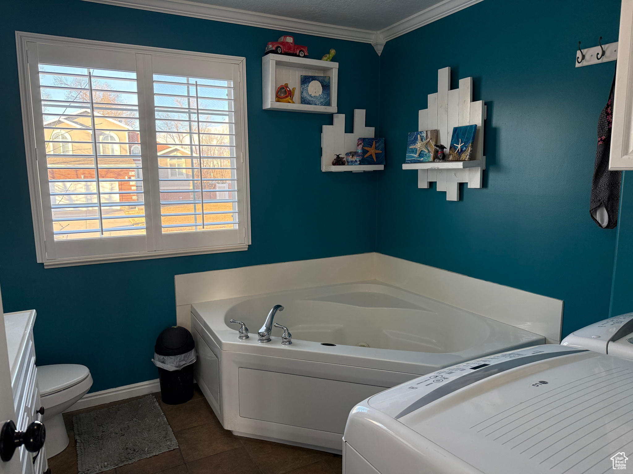 Bathroom with tile patterned flooring, crown molding, a tub, and toilet