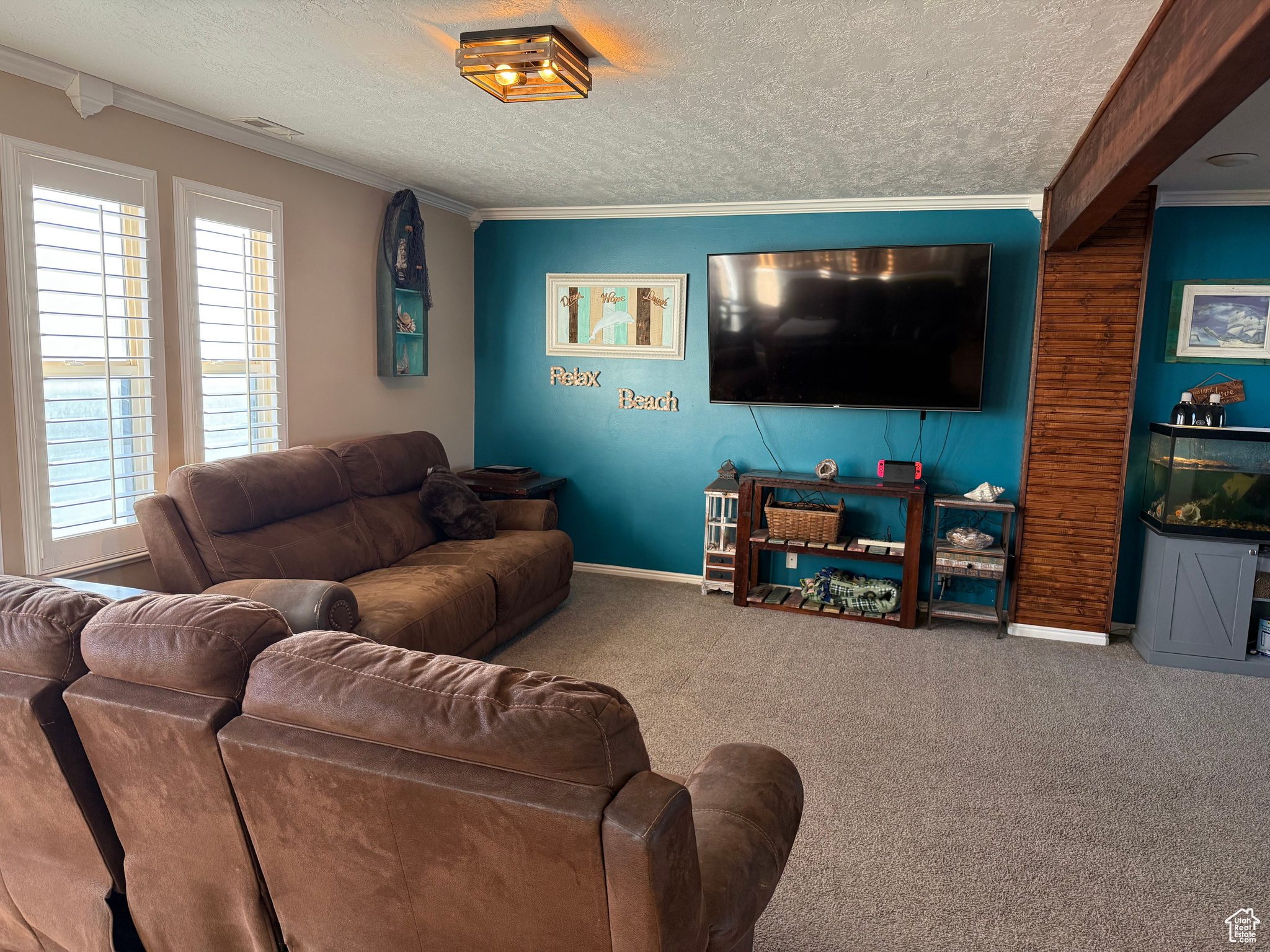 Living room with ornamental molding, a textured ceiling, and carpet