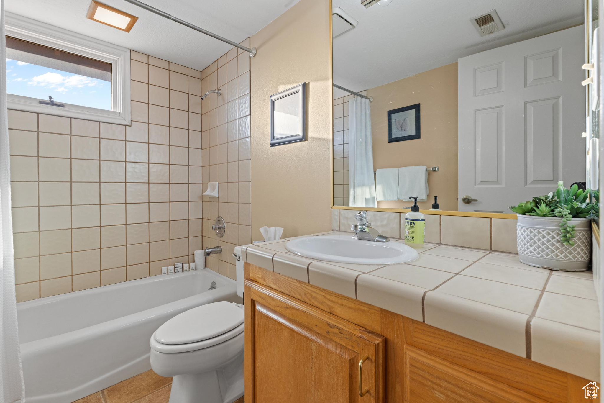 Full bathroom with shower / bathtub combination with curtain, vanity, toilet, and tile patterned floors