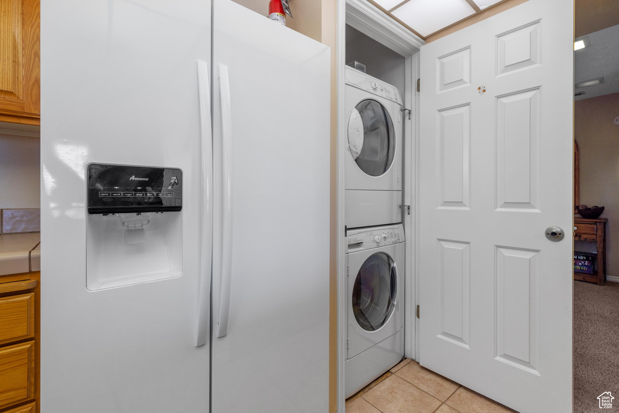 Clothes washing area featuring stacked washer / dryer and light tile patterned floors