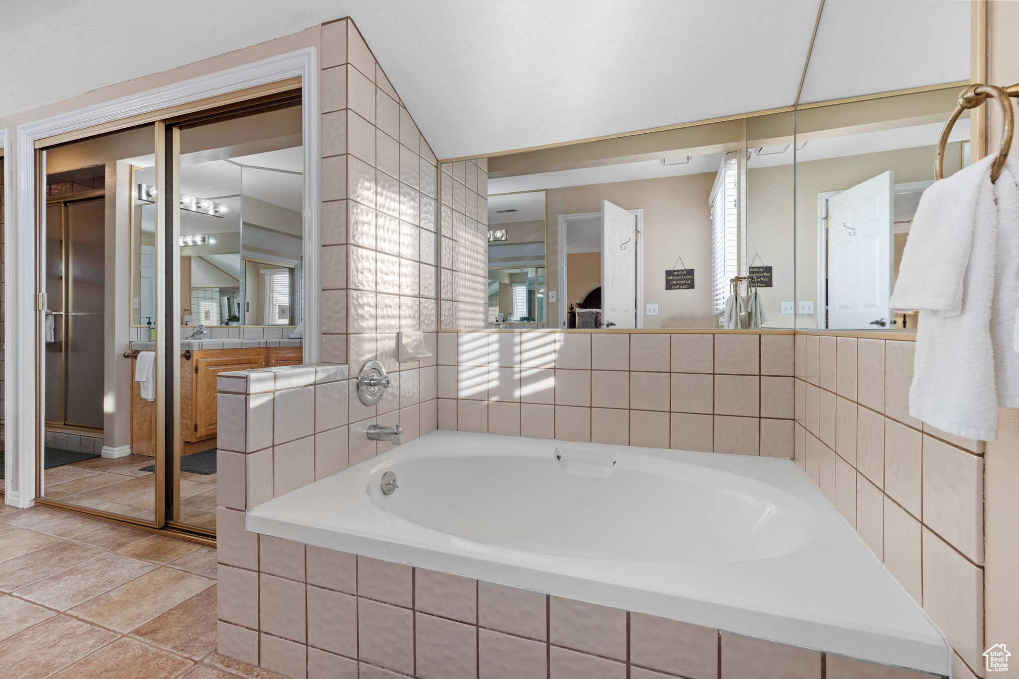 Bathroom with tiled tub and tile patterned floors