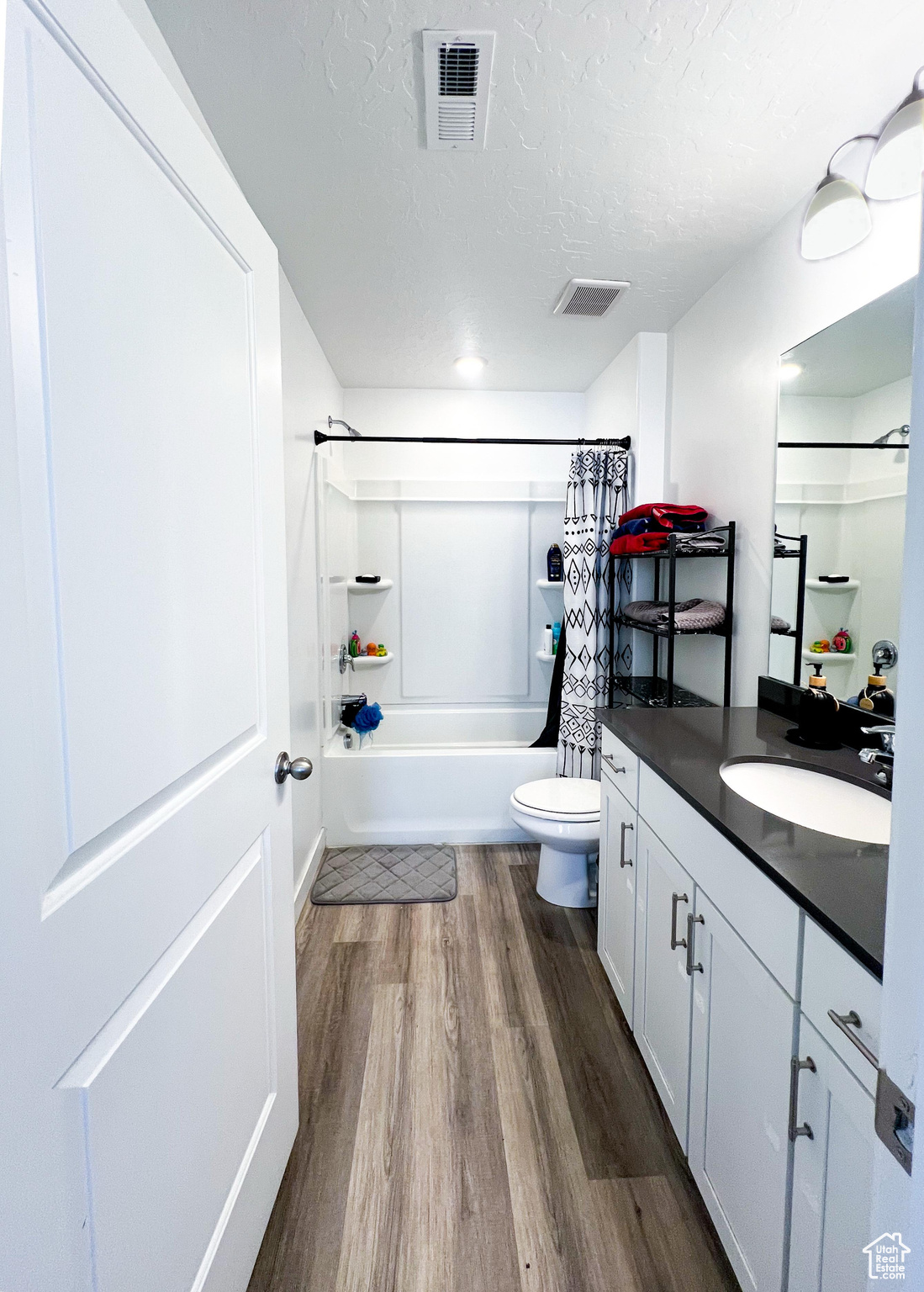 Full master bathroom with shower / bath combination with curtain, hardwood / wood-style flooring, vanity, toilet, and a textured ceiling