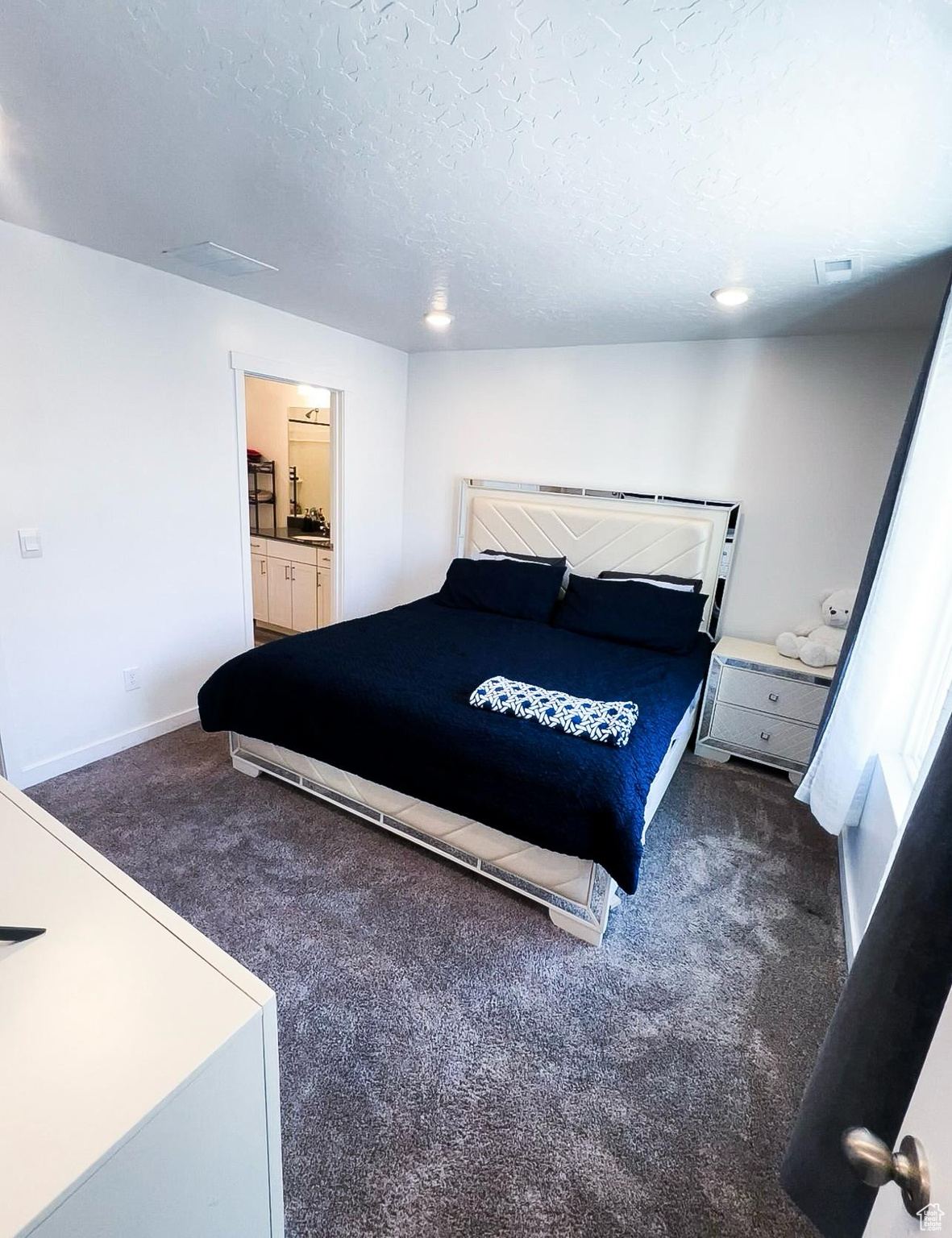 Master Bedroom with dark colored carpet, connected bathroom, and a textured ceiling