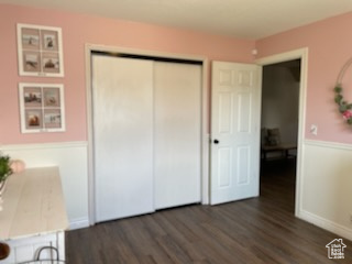 Unfurnished bedroom featuring dark hardwood / wood-style floors and a closet