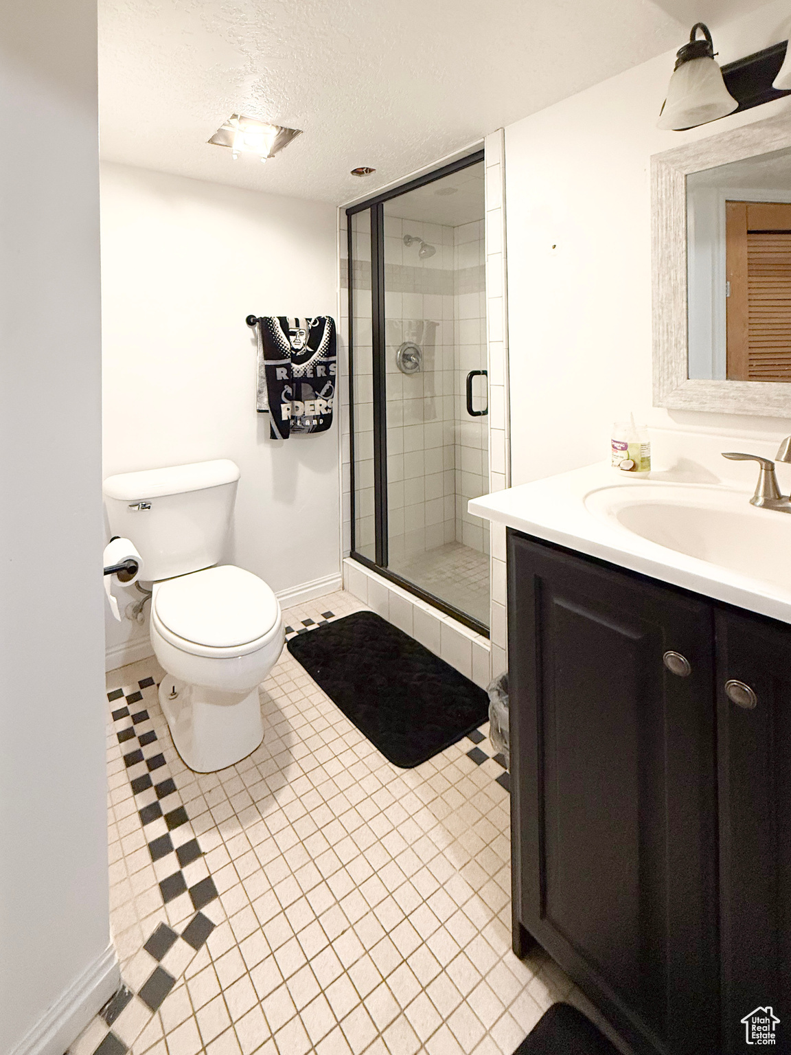 Bathroom with vanity, a textured ceiling, a shower with door, and toilet