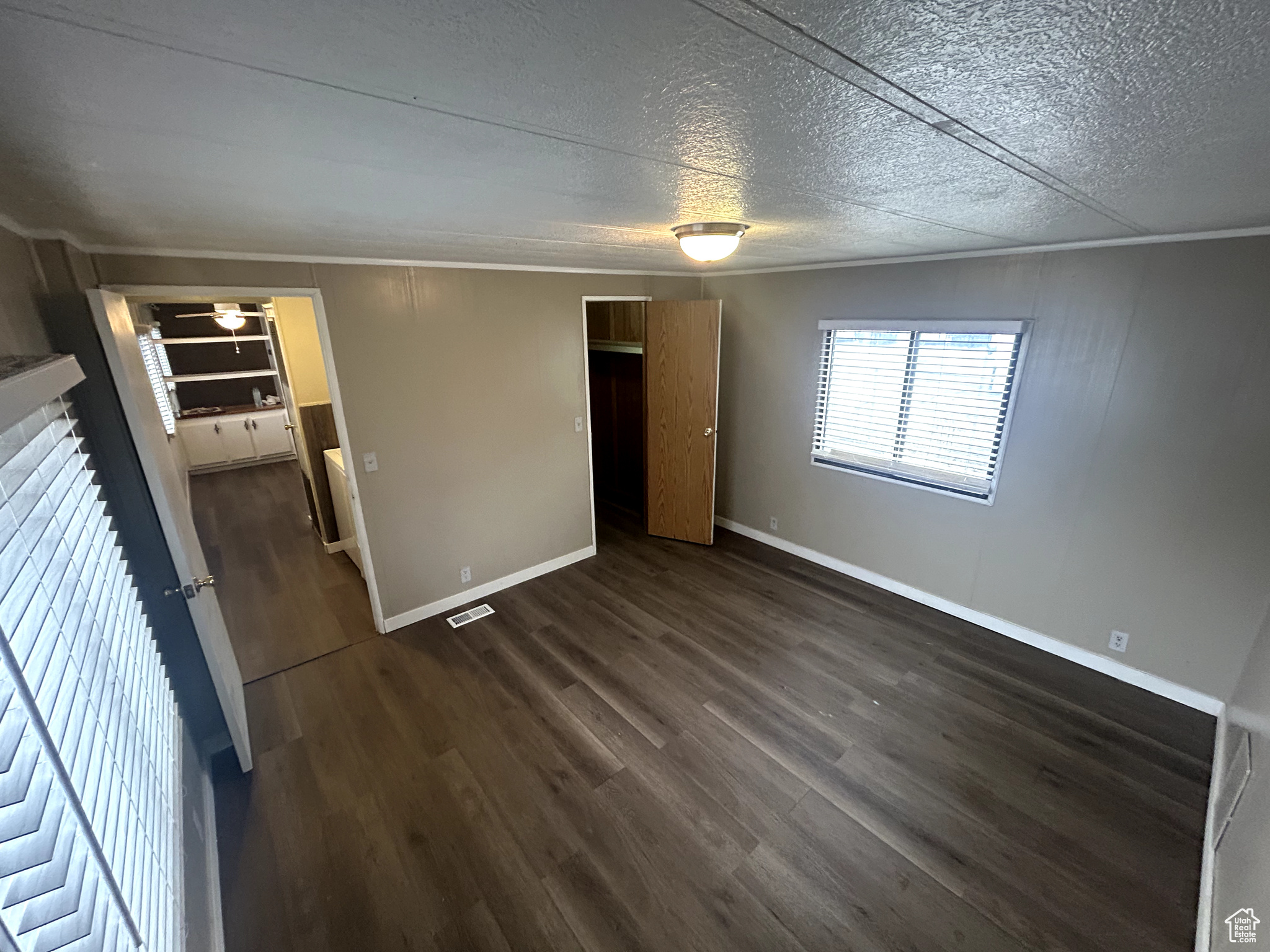 Unfurnished bedroom featuring crown molding, dark hardwood / wood-style floors, and a textured ceiling
