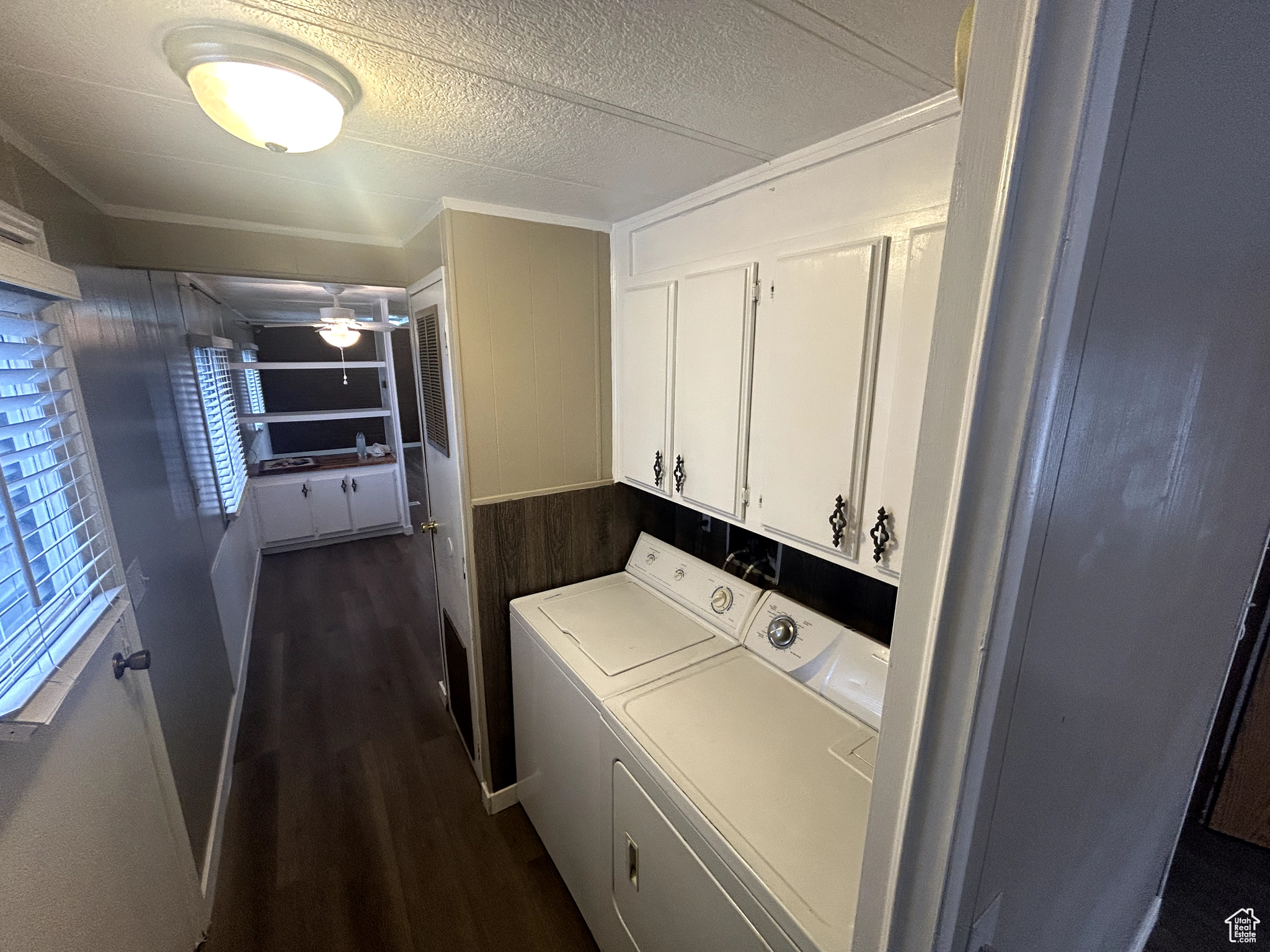 Laundry area featuring crown molding, dark wood-type flooring, cabinets, independent washer and dryer, and a textured ceiling