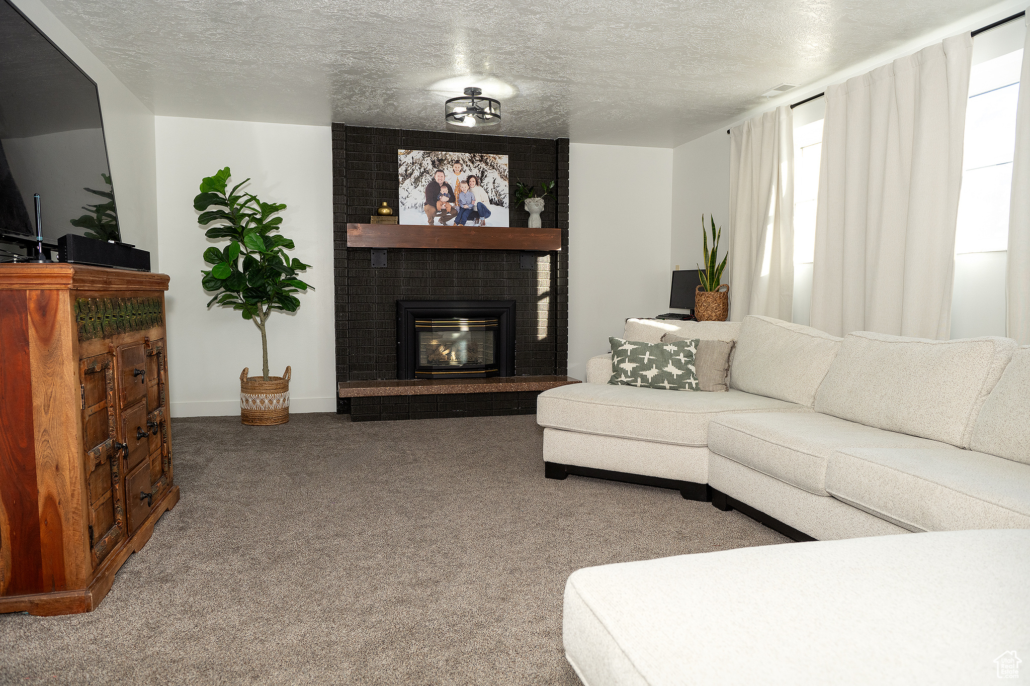 Carpeted living room with a brick fireplace and a textured ceiling