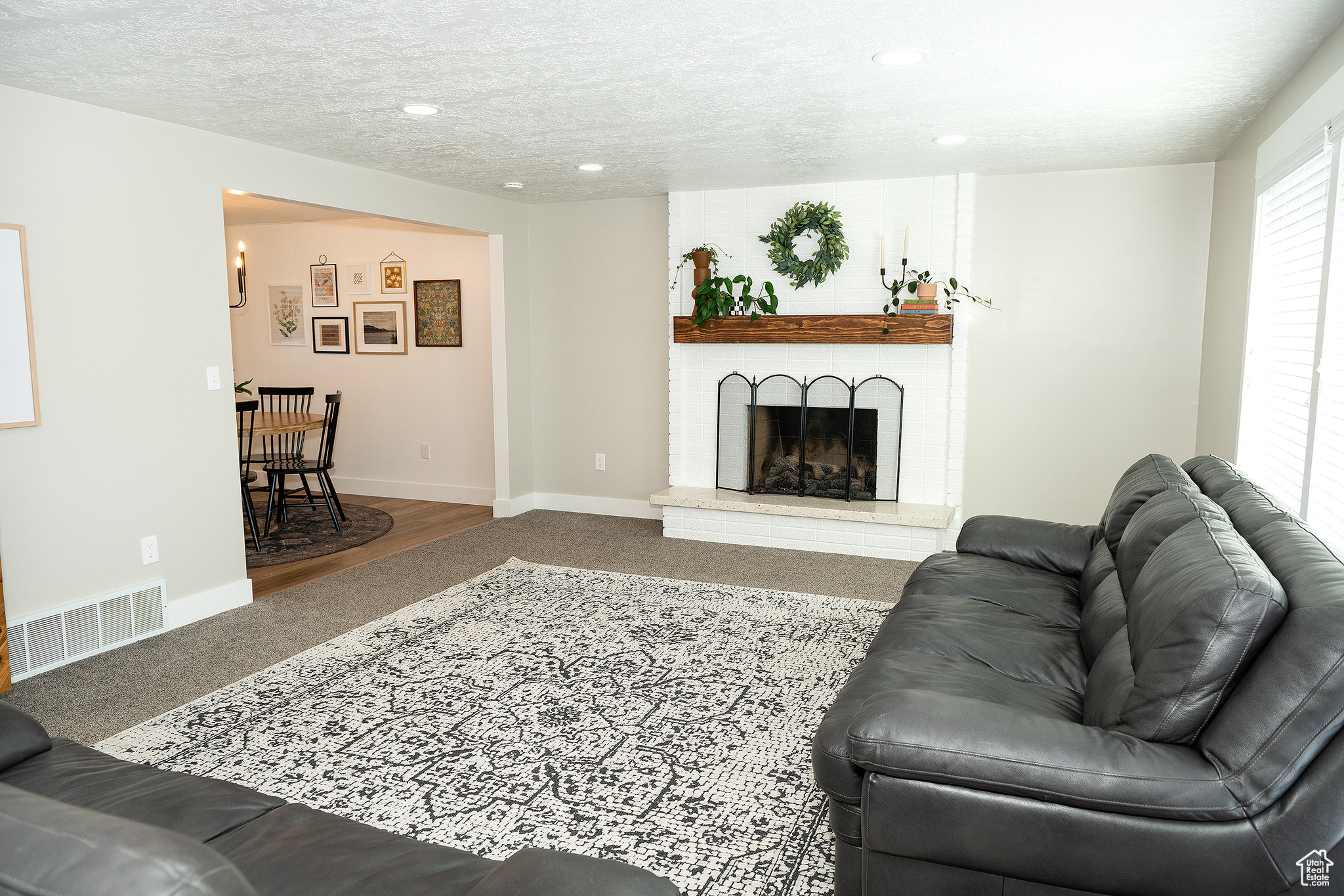 Living room with carpet, a brick fireplace, and a textured ceiling