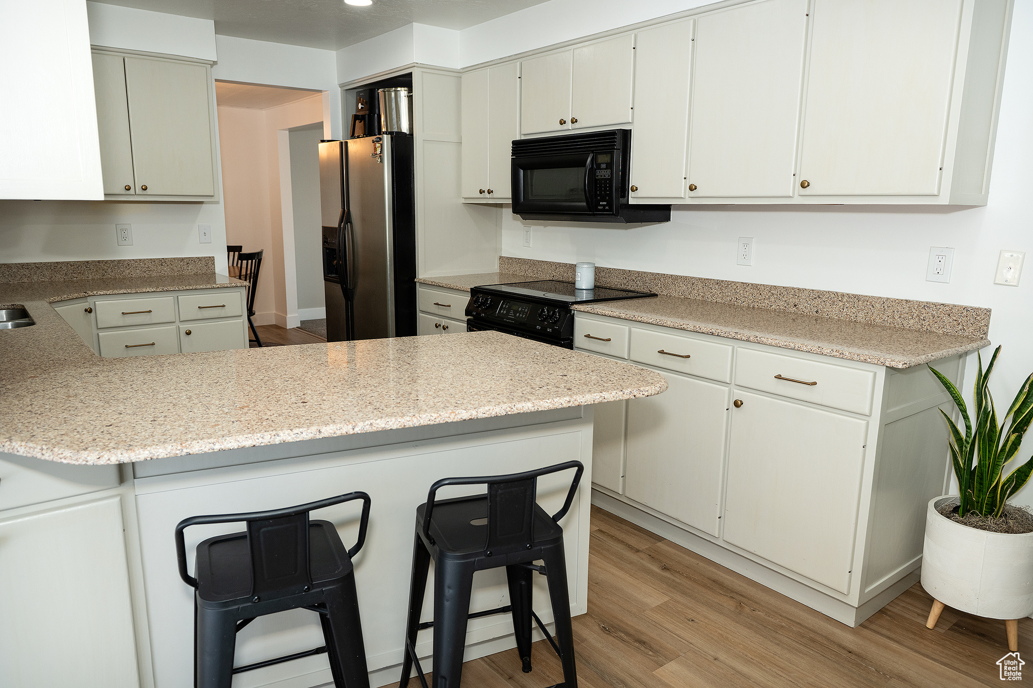 Kitchen with black appliances, kitchen peninsula, and white cabinets