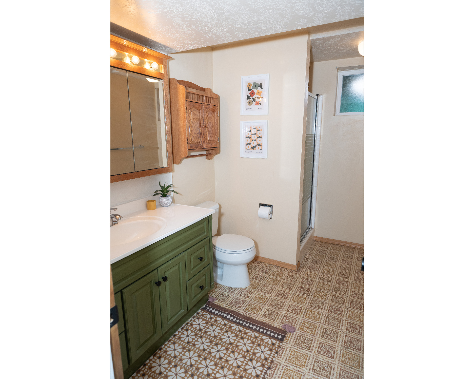 Full bathroom with a textured ceiling, toilet, vanity, baseboards, and a stall shower