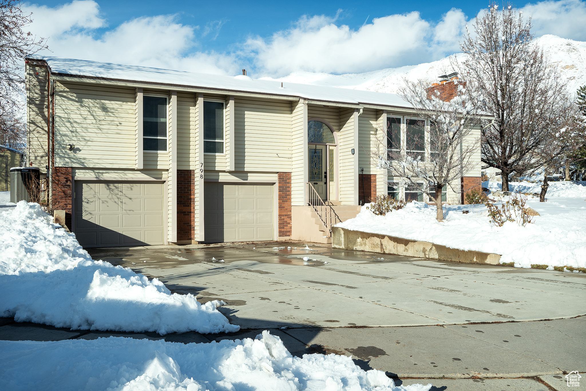 Split foyer home featuring driveway, brick siding, and a chimney