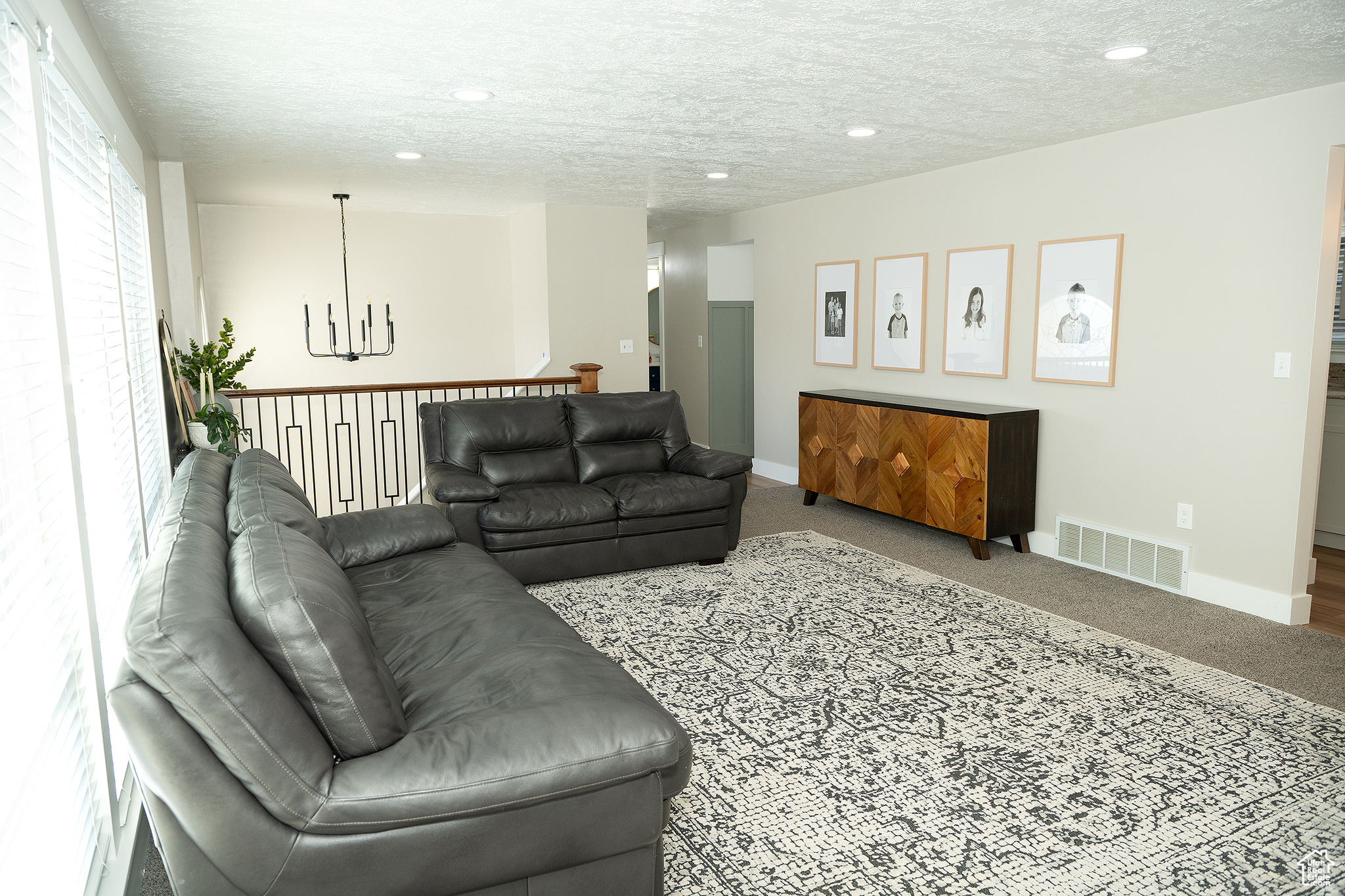 Carpeted living room featuring a notable chandelier and a textured ceiling