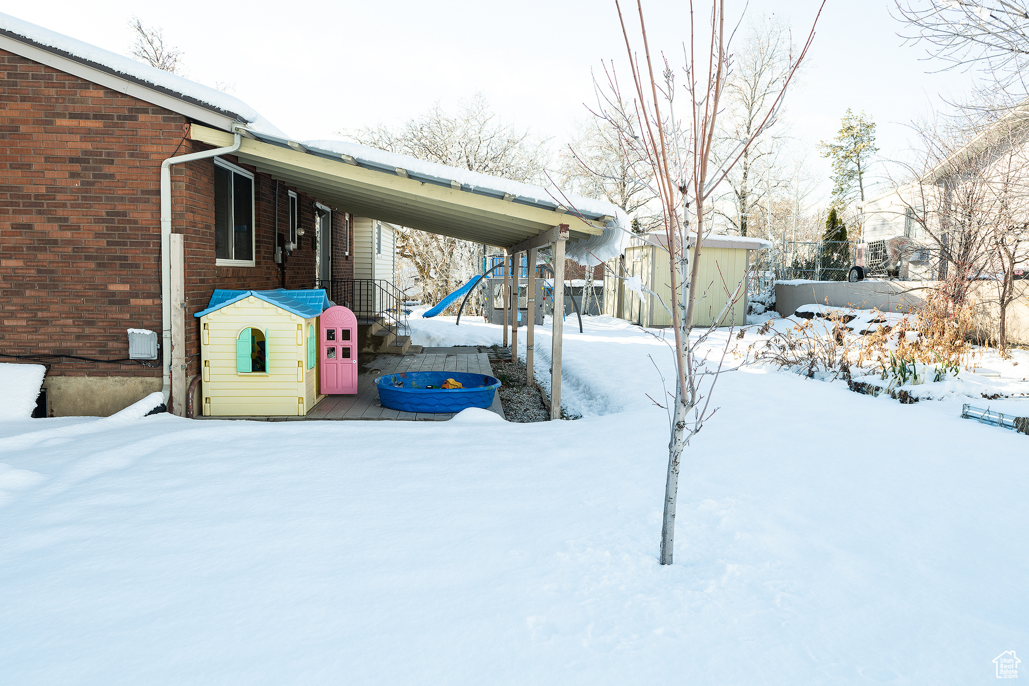 Yard covered in snow with a storage unit and an outbuilding