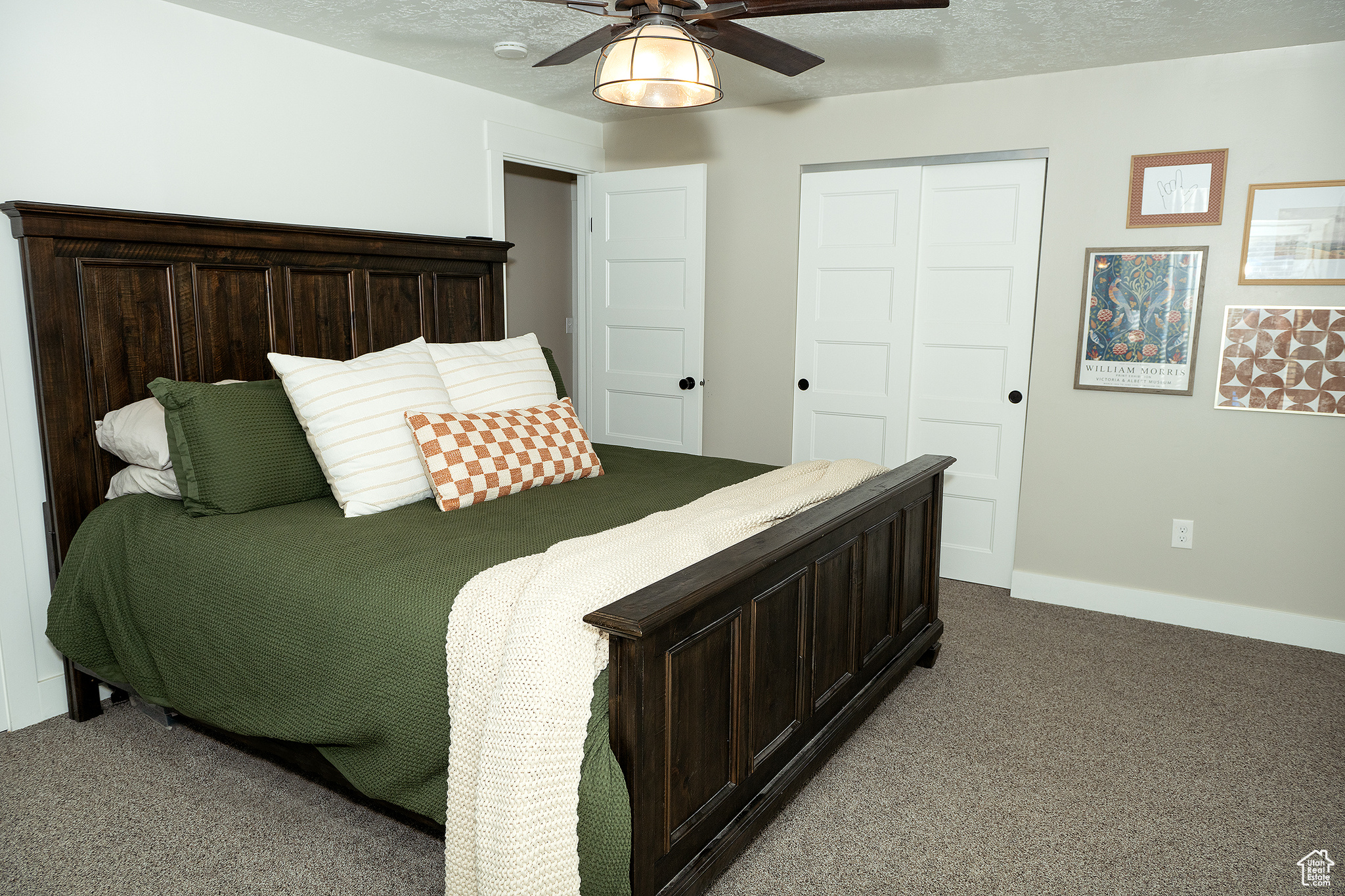 Carpeted bedroom with ceiling fan, a textured ceiling, and a closet