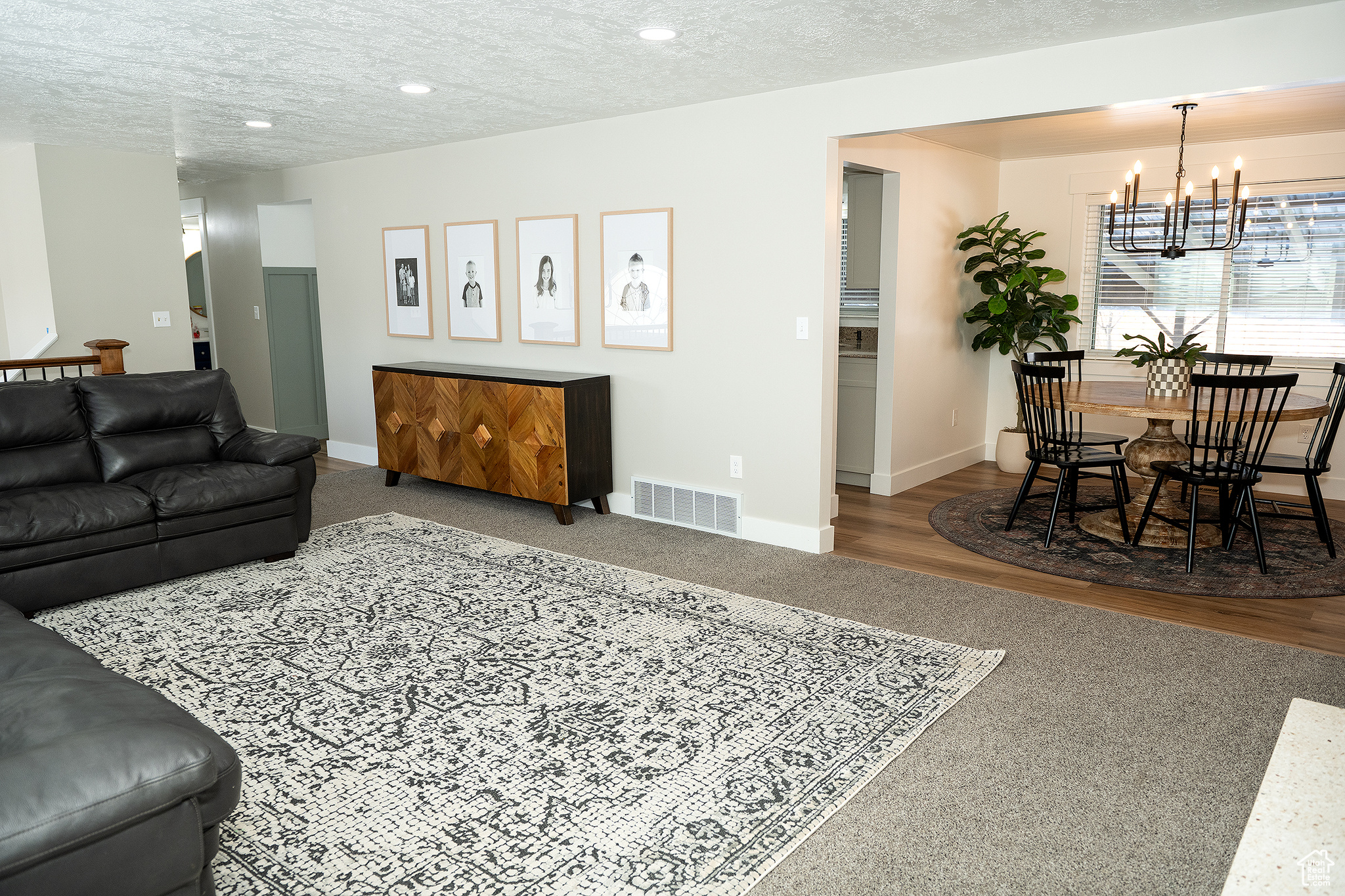 Living room with hardwood / wood-style floors, a notable chandelier, and a textured ceiling