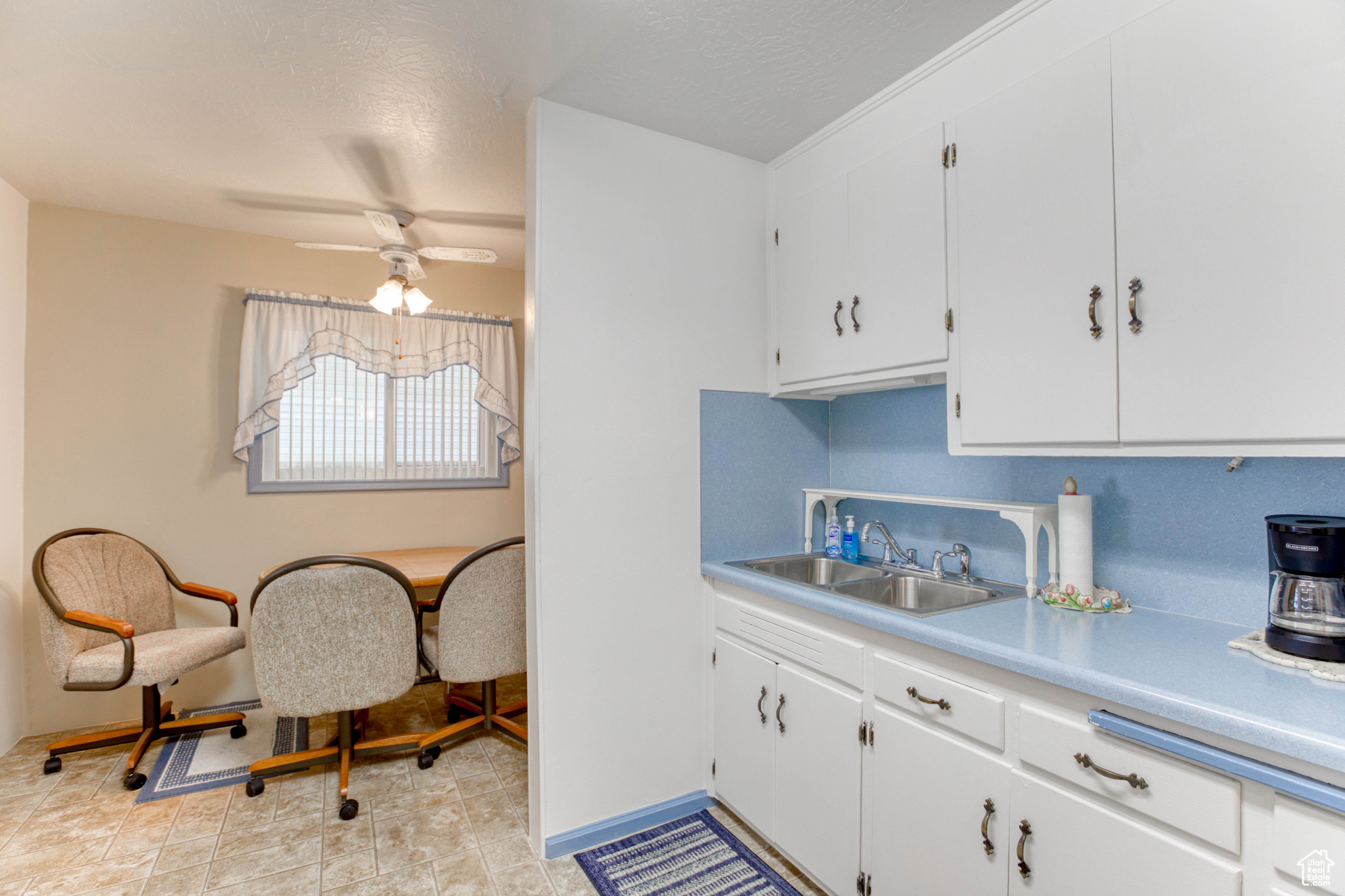 Kitchen with sink, ceiling fan, backsplash, a textured ceiling, and white cabinets