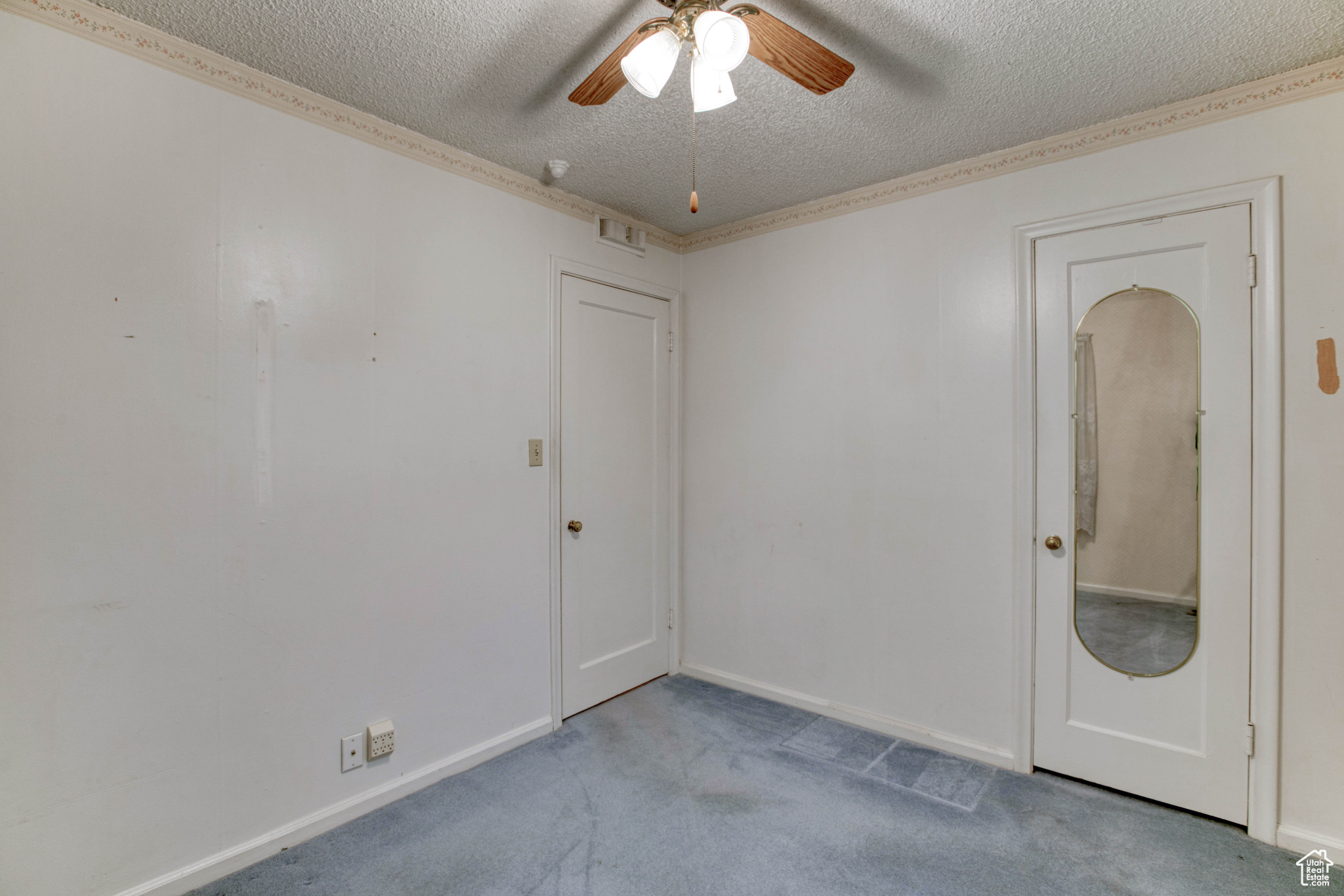 Carpeted spare room with ceiling fan and a textured ceiling