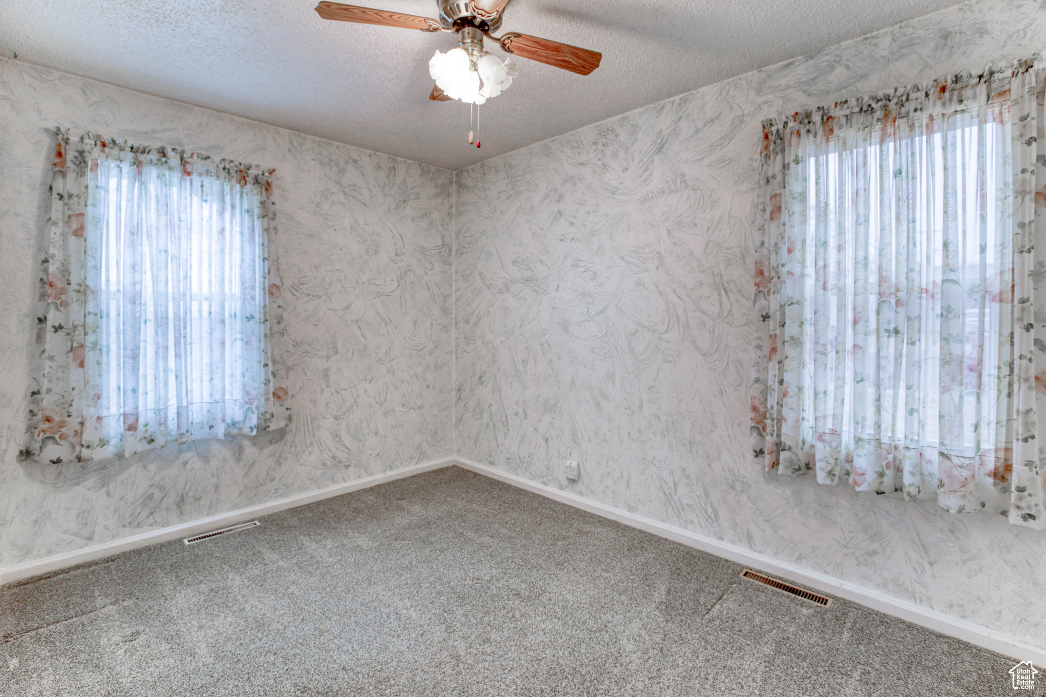 Unfurnished room featuring ceiling fan, plenty of natural light, a textured ceiling, and carpet flooring