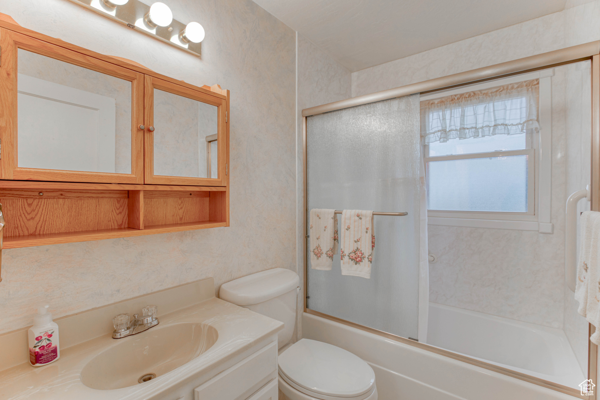 Full bathroom with vanity, shower / bath combination with glass door, and toilet
