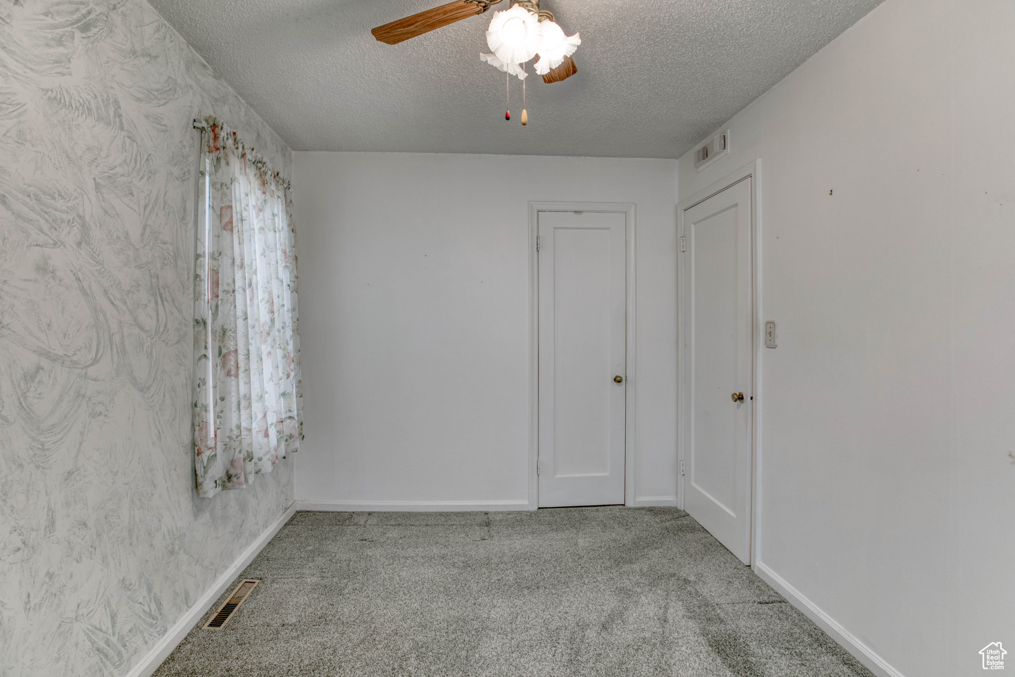 Unfurnished room with ceiling fan, light colored carpet, and a textured ceiling