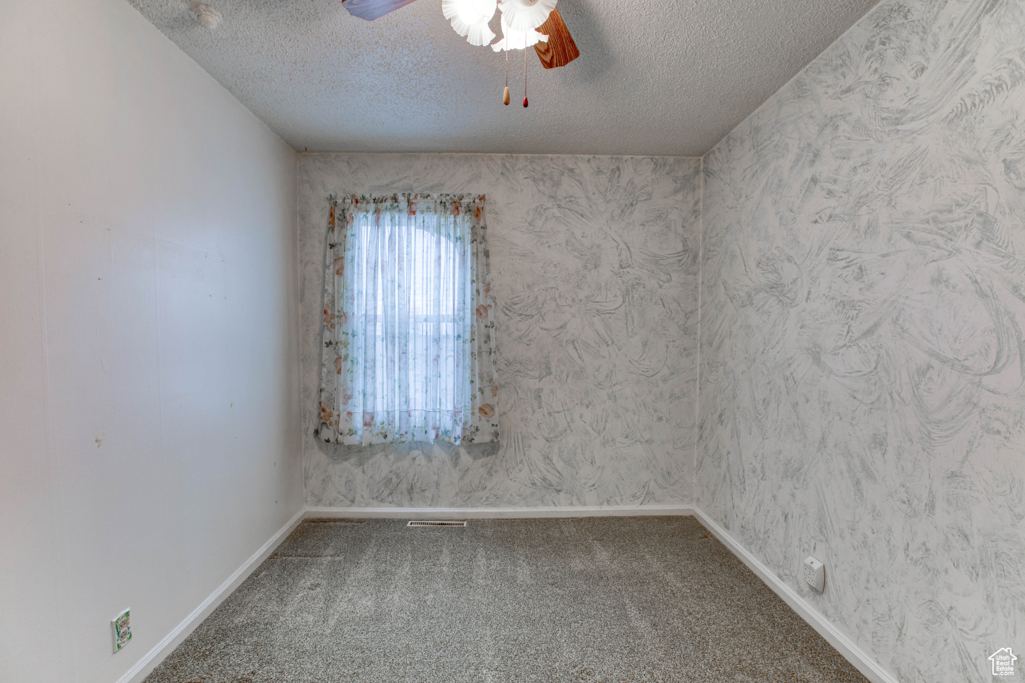 Carpeted spare room with ceiling fan and a textured ceiling