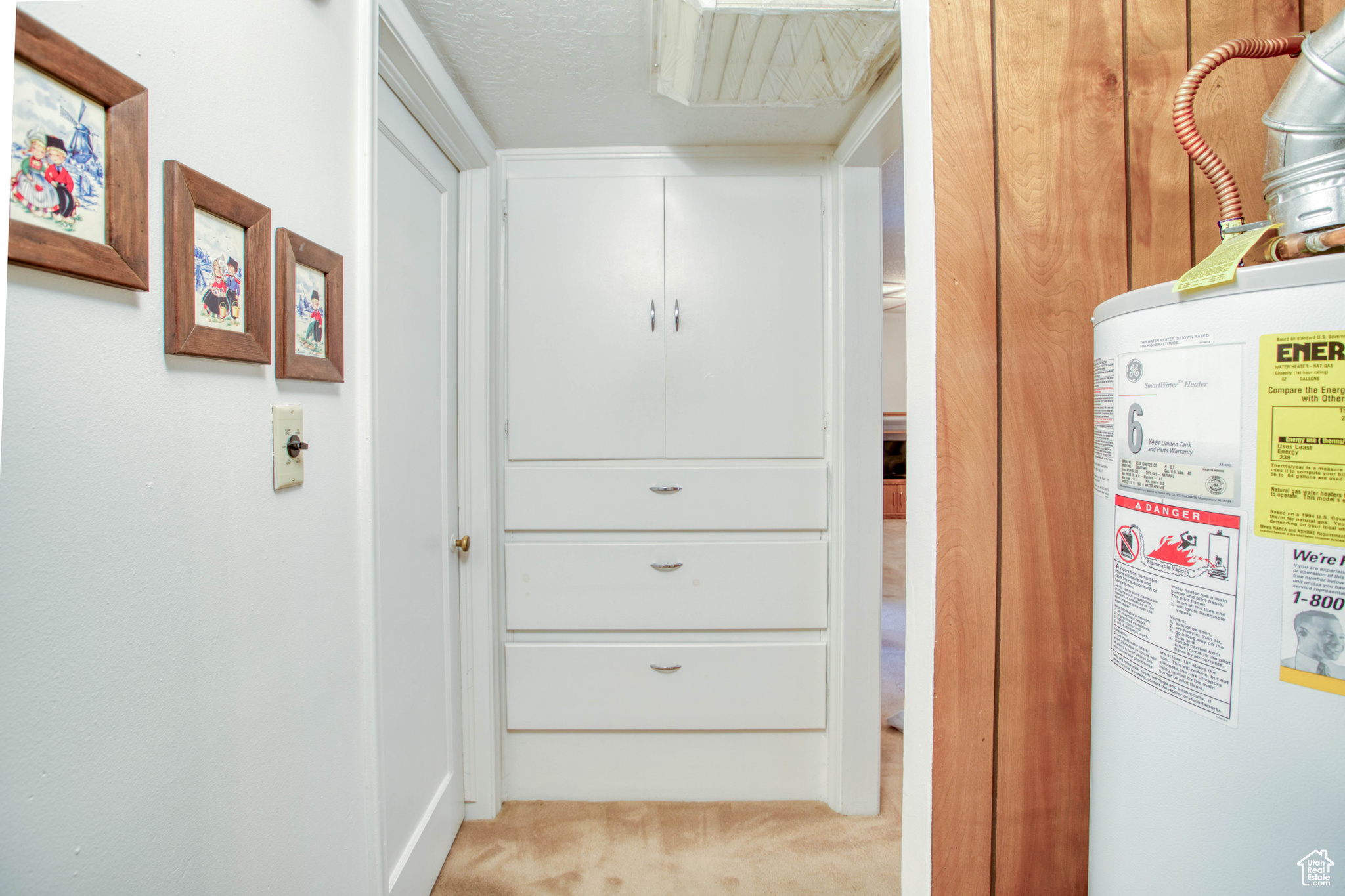 Hall with water heater, light carpet, and a textured ceiling