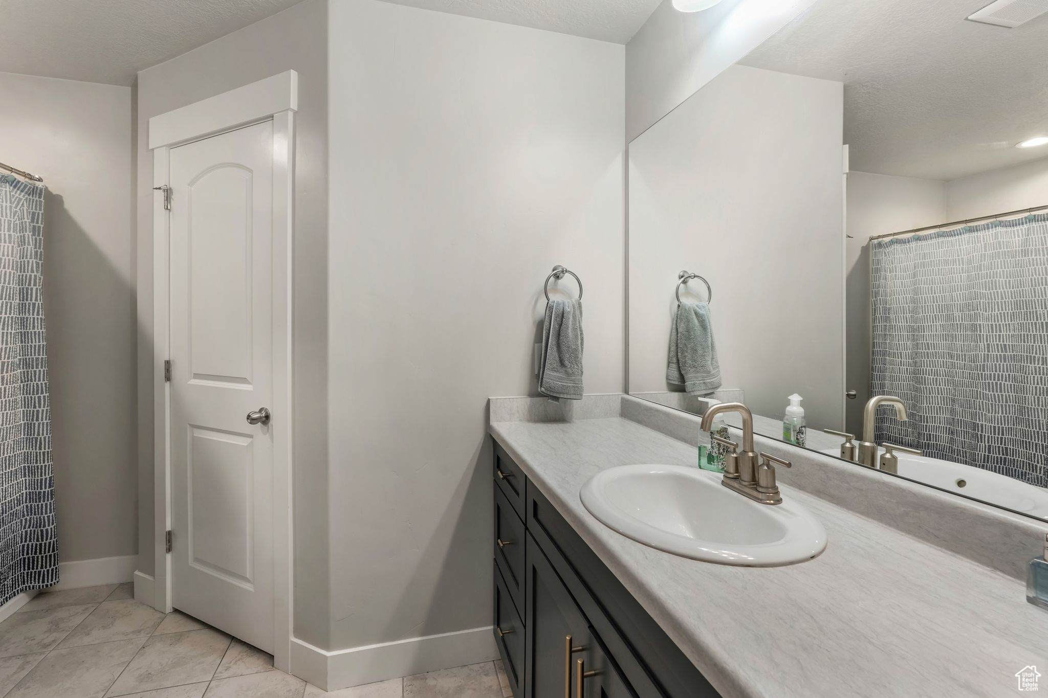 Bathroom with vanity, tile patterned flooring, and a shower with shower curtain