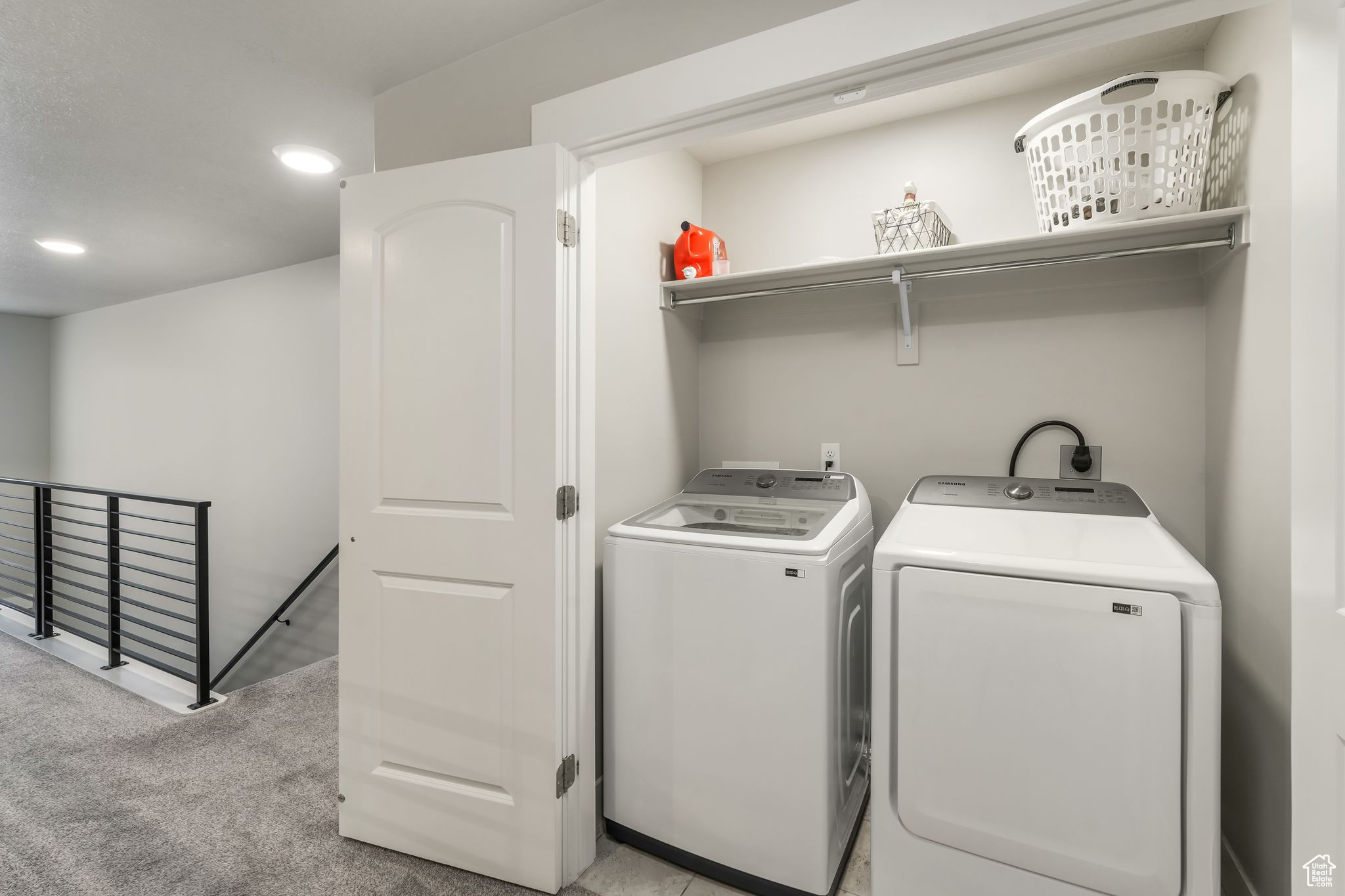 Laundry room featuring washing machine and clothes dryer and light colored carpet