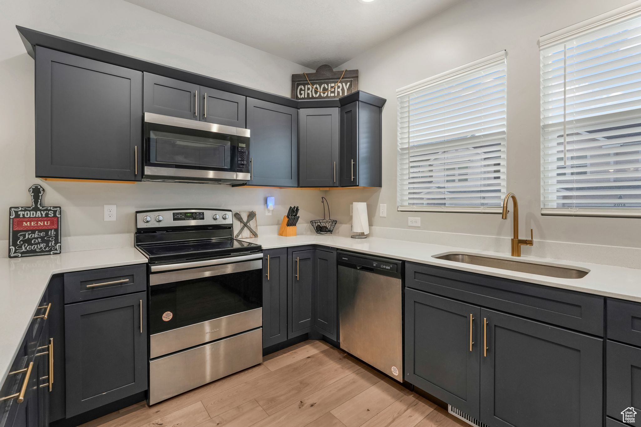 Kitchen with appliances with stainless steel finishes, sink, and light hardwood / wood-style floors