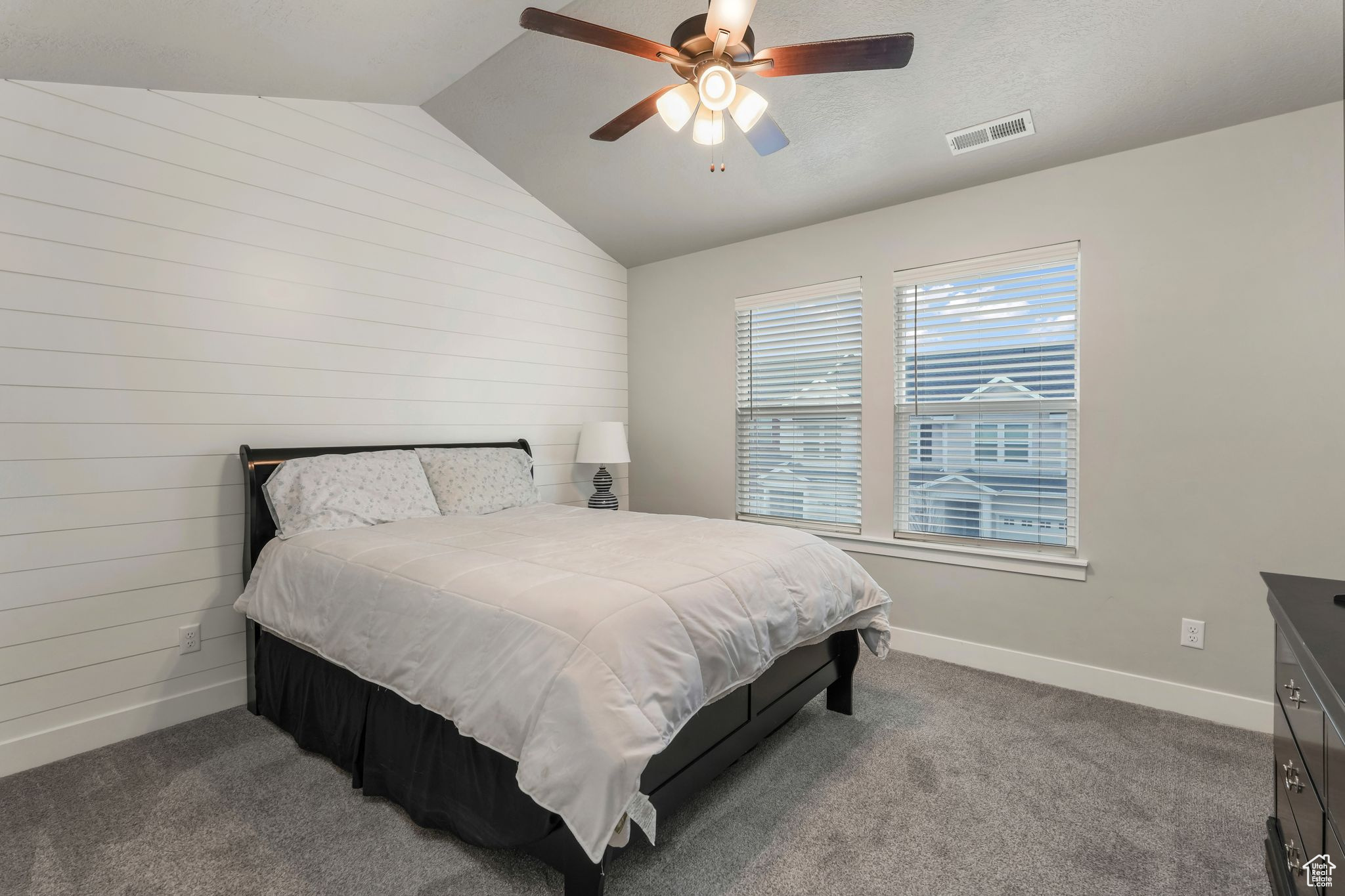 Bedroom with vaulted ceiling, ceiling fan, wooden walls, and carpet floors