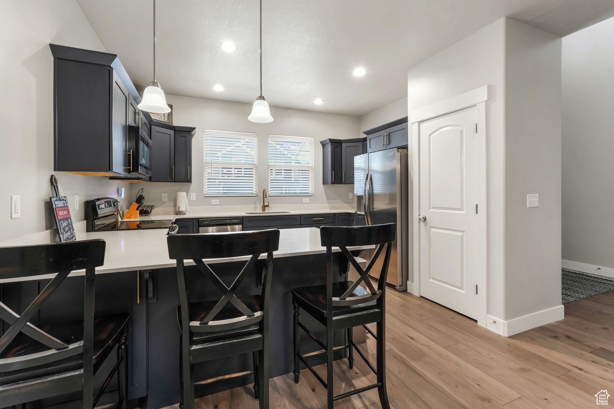 Kitchen featuring pendant lighting, sink, a kitchen breakfast bar, stainless steel appliances, and light wood-type flooring