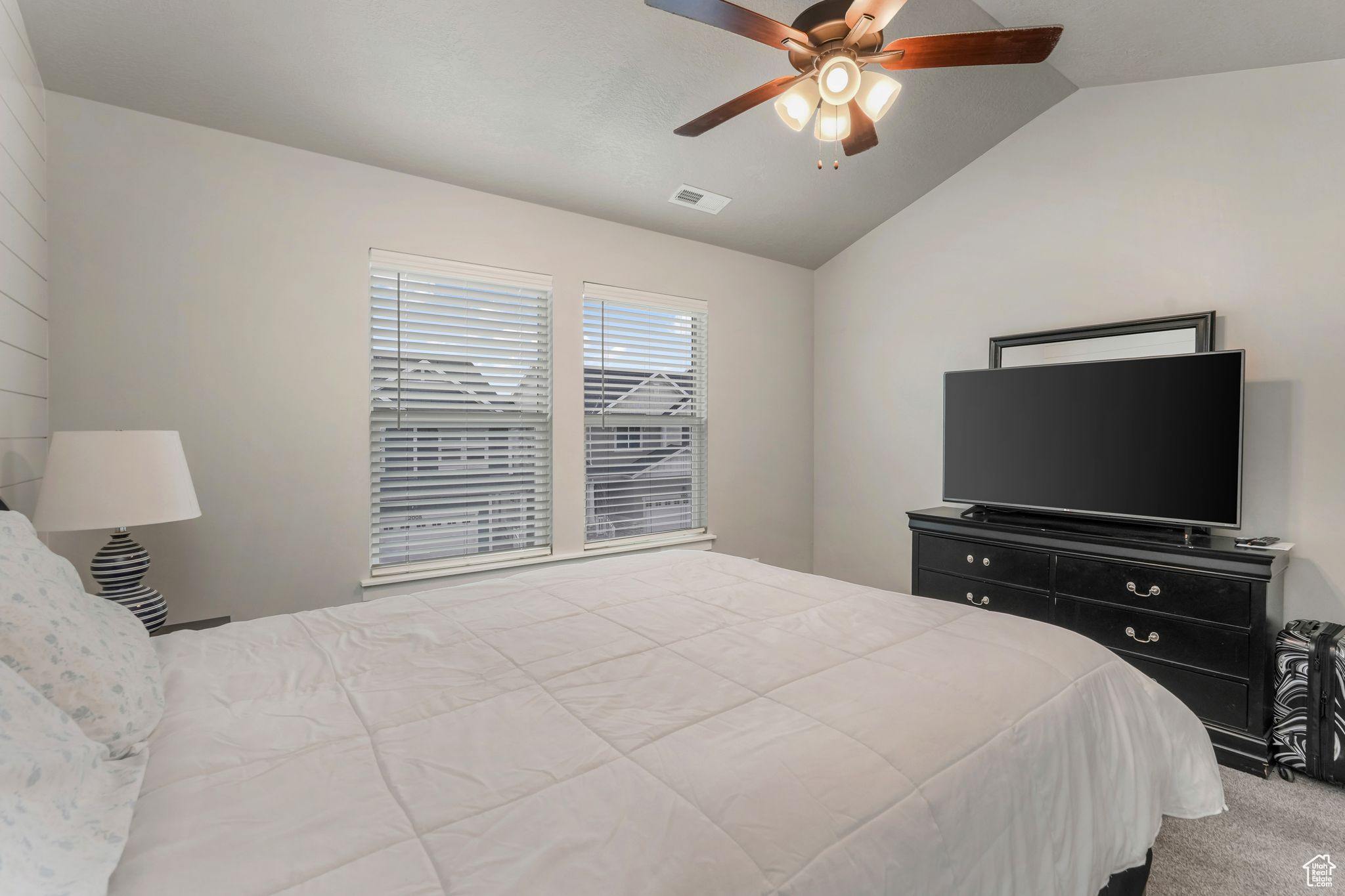 Bedroom with vaulted ceiling, ceiling fan, and carpet flooring