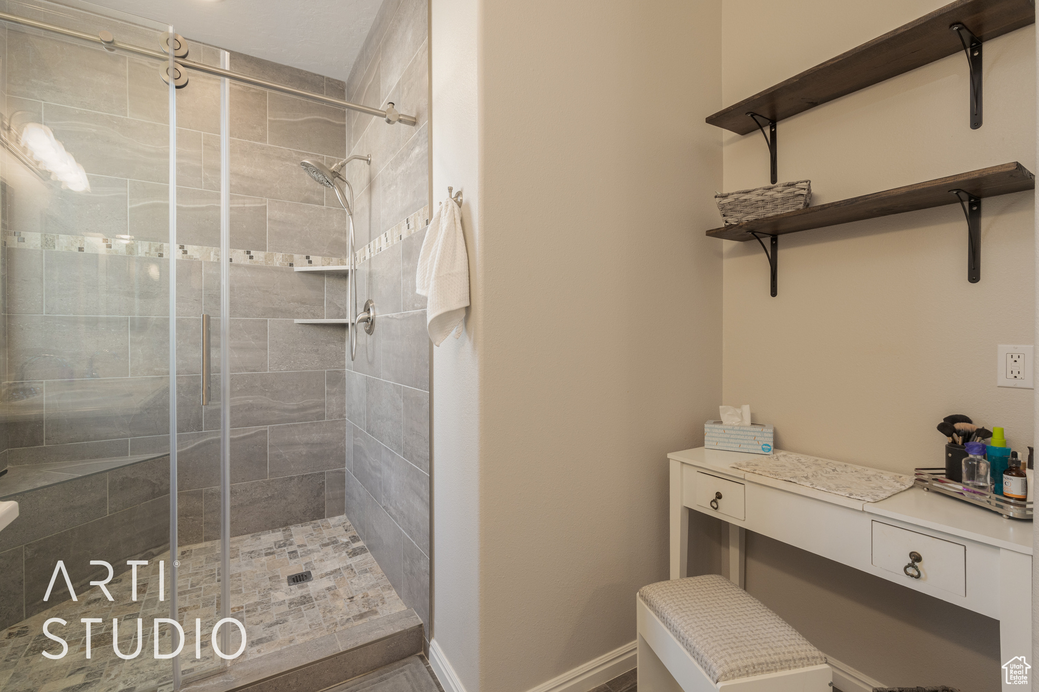 primary bathroom featuring a custom tile shower and vanity space