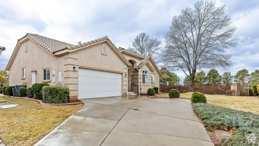 View of front of home with a front yard, central AC unit, and a garage