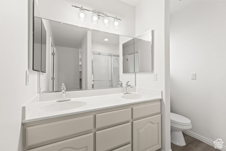 Bathroom with toilet, wood-type flooring, a shower with shower door, and vanity
