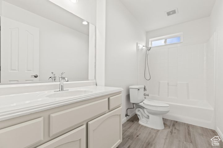 Full bathroom featuring wood-type flooring, vanity, tub / shower combination, and toilet