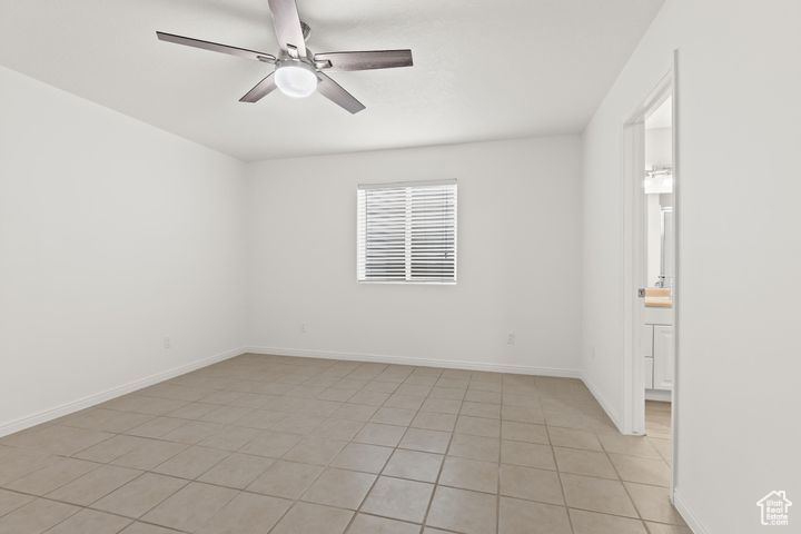 Empty room featuring light tile patterned flooring and ceiling fan
