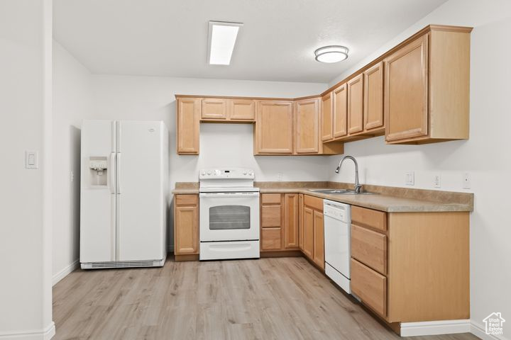 Kitchen featuring sink, white appliances, light brown cabinetry, and light hardwood / wood-style floors