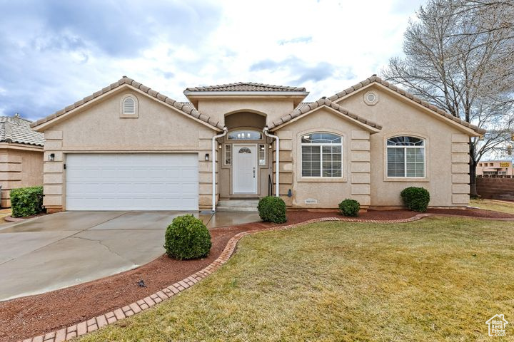 Mediterranean / spanish-style home with a front yard and a garage