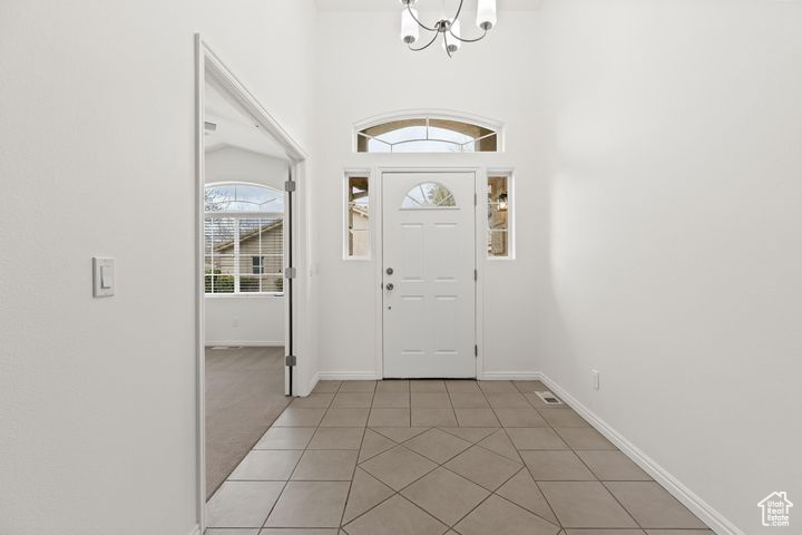 Foyer entrance with light tile patterned flooring and an inviting chandelier