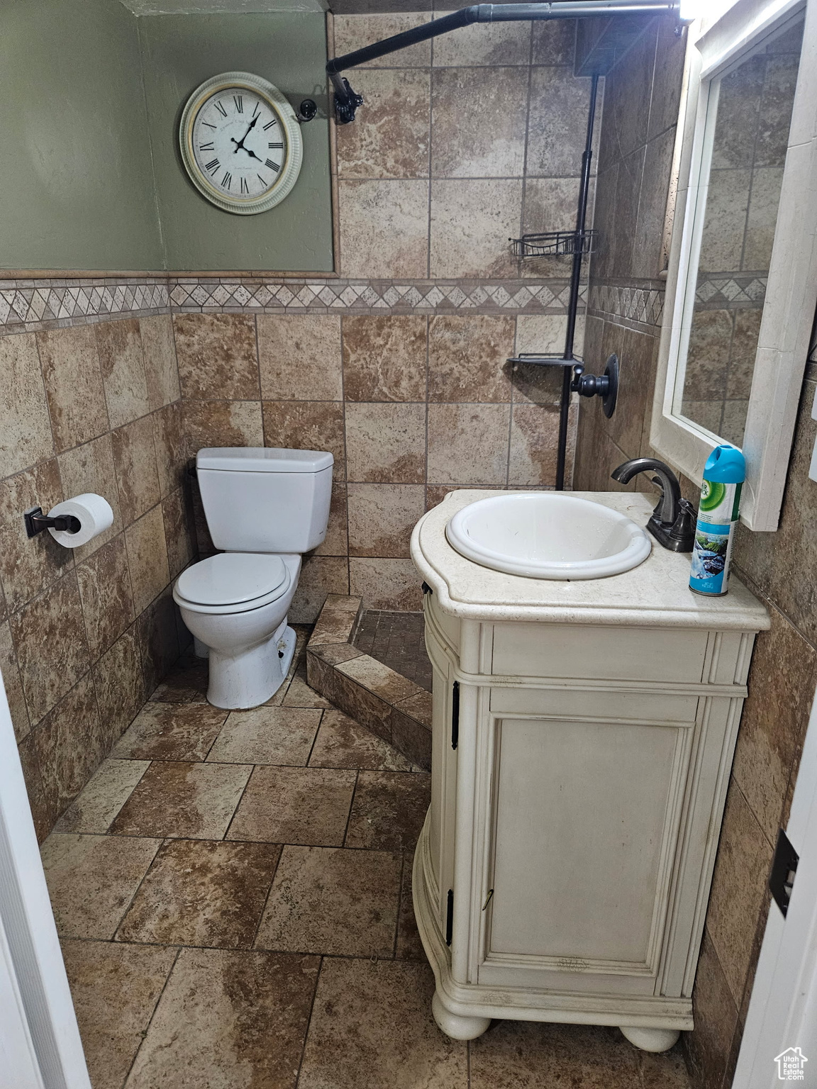 Bathroom with vanity, tile walls, stone tile floors, and toilet