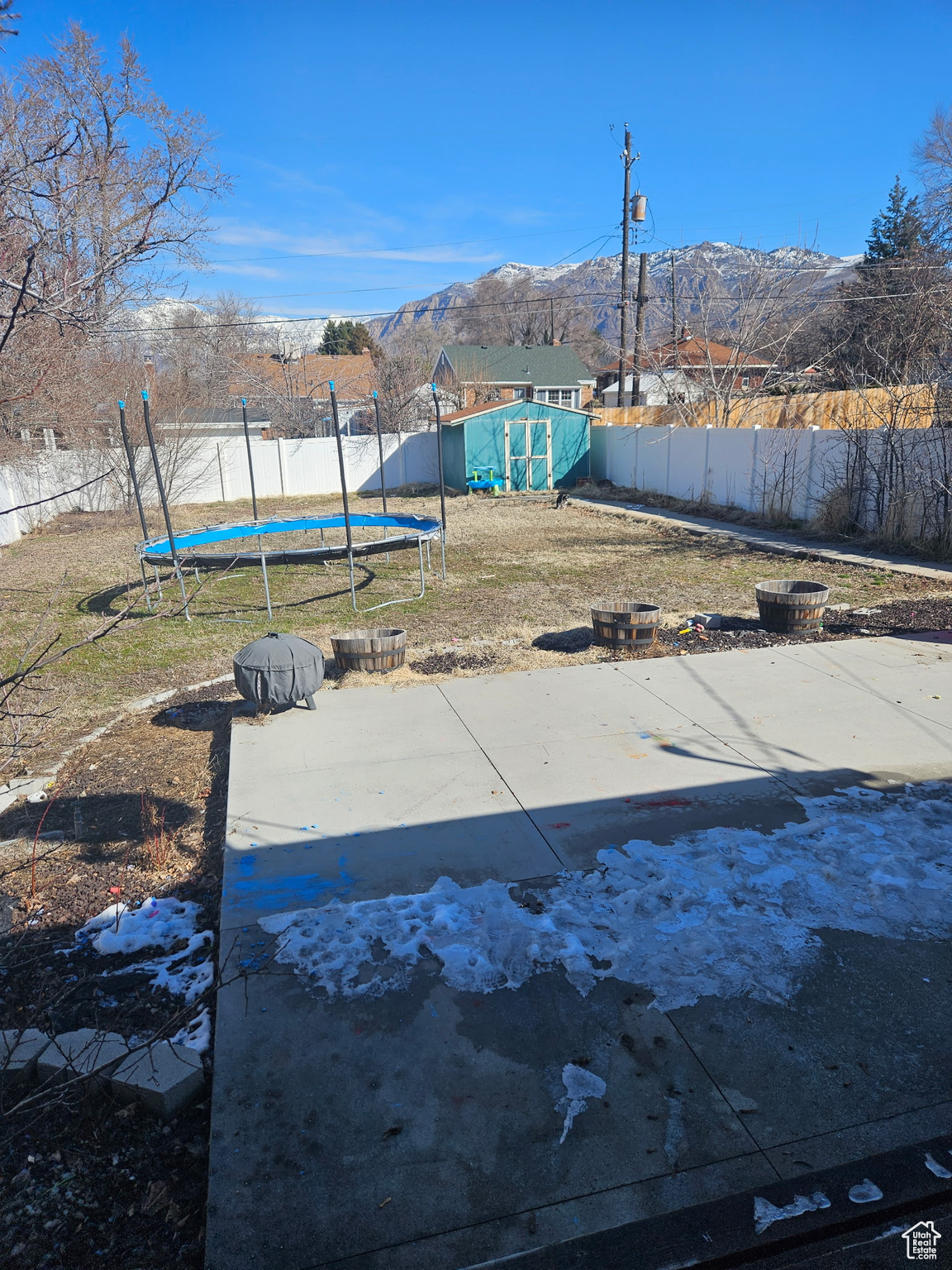 View of yard with a trampoline, a storage shed, a fenced backyard, an outbuilding, and a mountain view