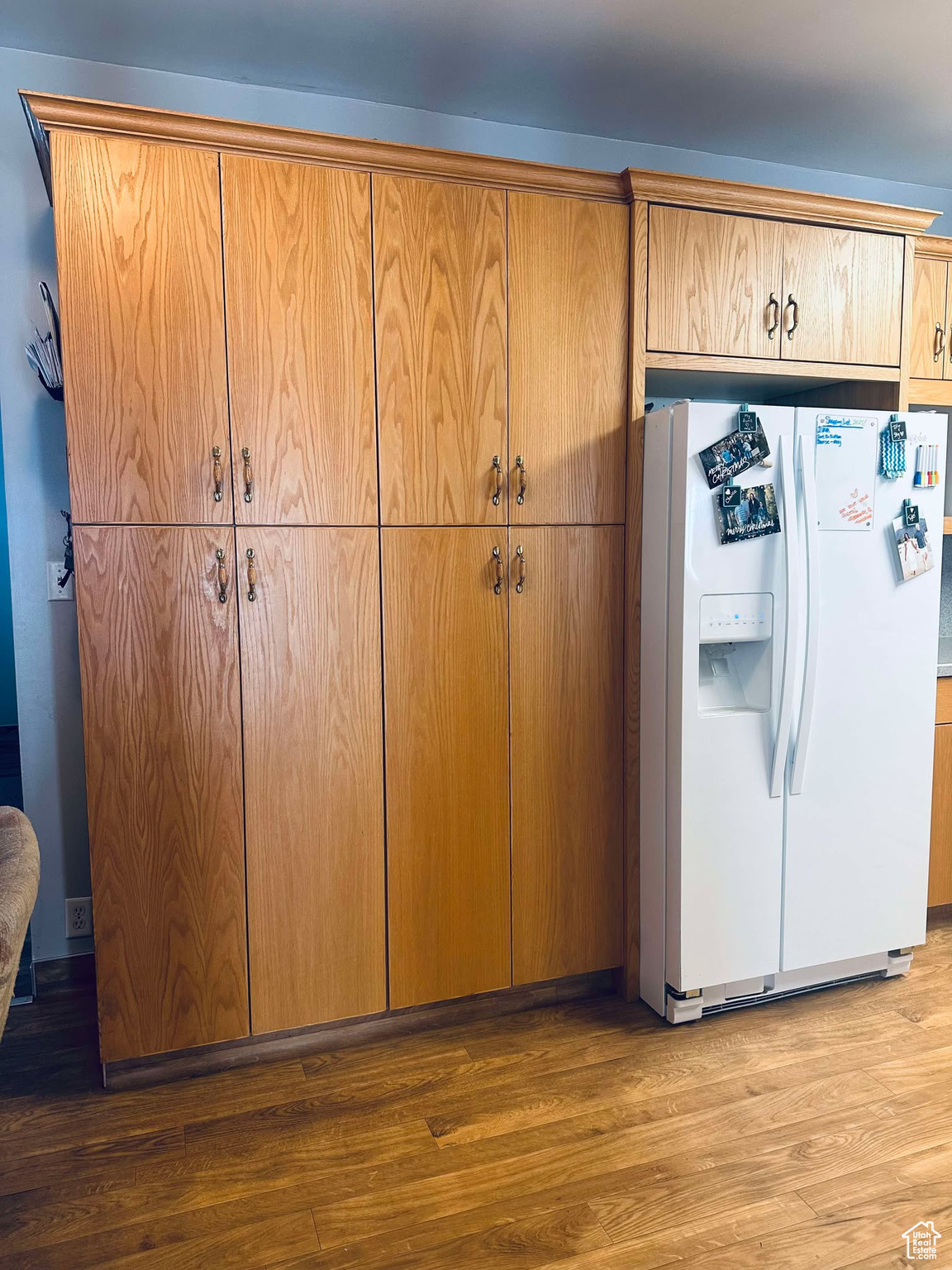 Kitchen with light hardwood / wood-style flooring and white fridge with ice dispenser
