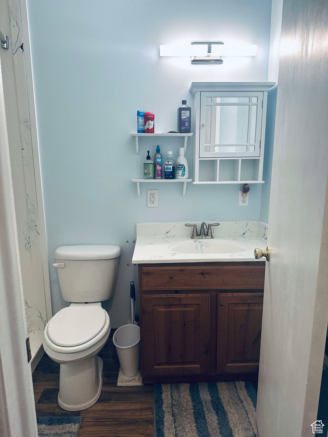 Bathroom with toilet, vanity, wood-type flooring, and walk in shower