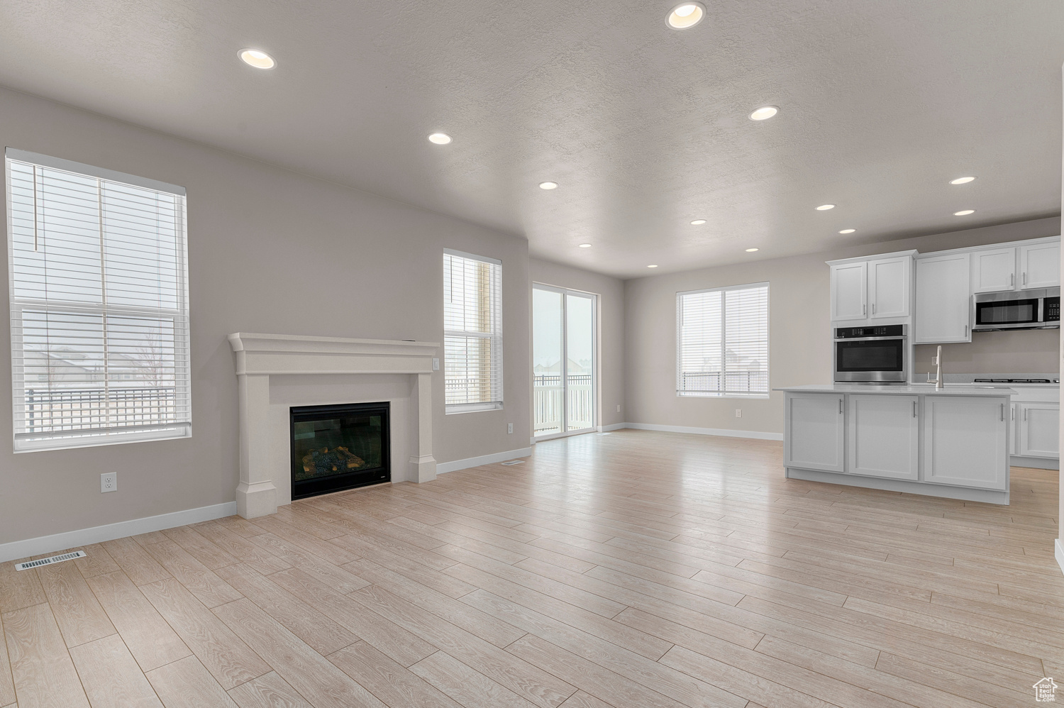 Unfurnished living room featuring light hardwood / wood-style flooring, a textured ceiling, and a healthy amount of sunlight