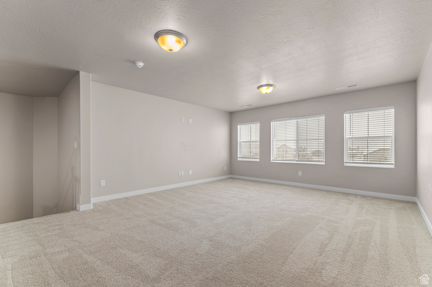 Spare room with light carpet and a textured ceiling